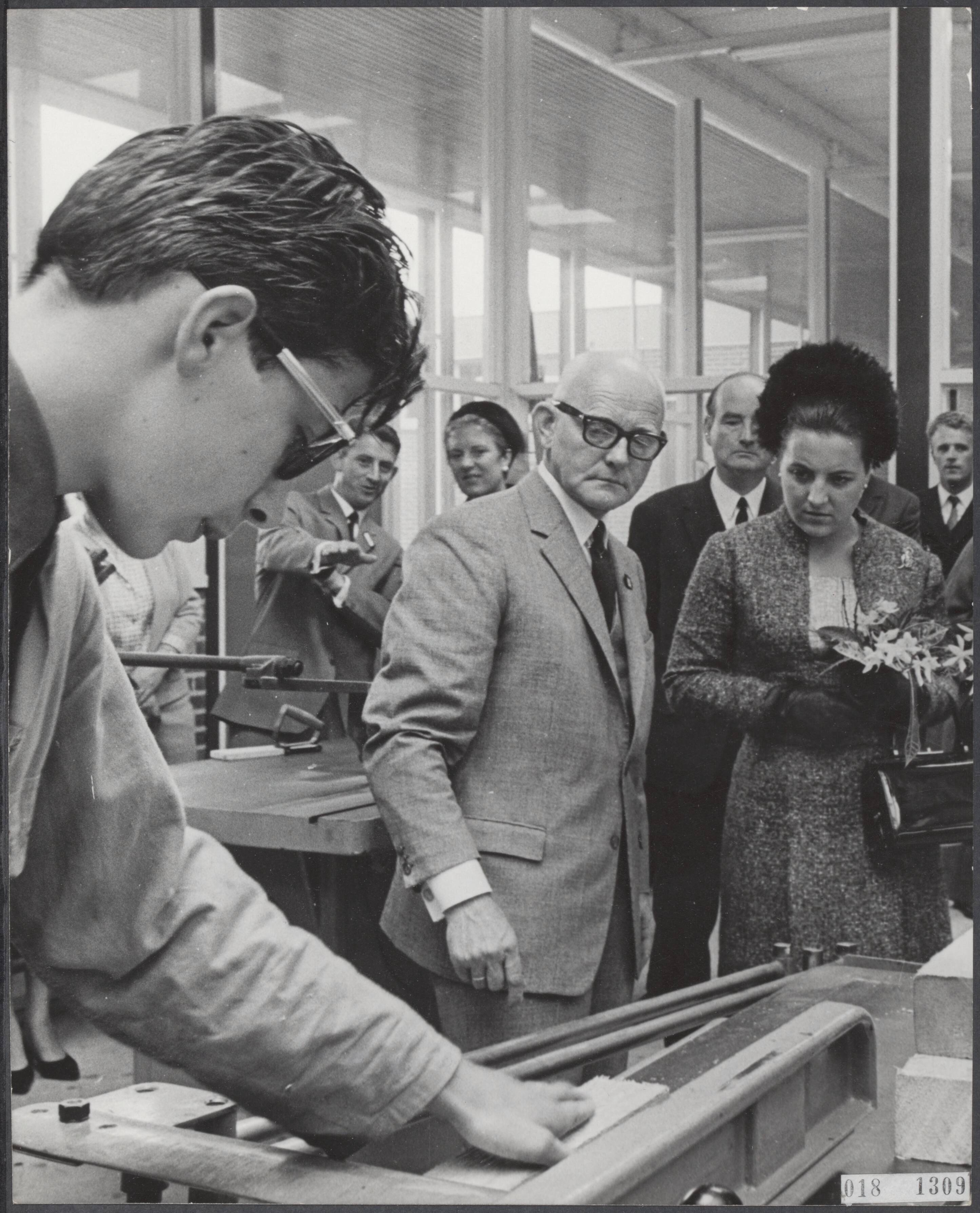 Fotocollectie Elsevier Binnenland — Prinses Margriet heeft een nieuwe L.T.S. geopend te Soest. De prinses kijkt tijdens de rondgang naar een timmerman in opleiding die een plank aan het zagen is. Naast haar de directeur van de L.T.S. Eemland — Foto: Kroon, Ron / Anefo. Licentie: Set B: Rechtenvrij / Publiek Domein. Bron: Nationaal Archief. http://hdl.handle.net/10648/adc4ec02-d0b4-102d-bcf8-003048976d84