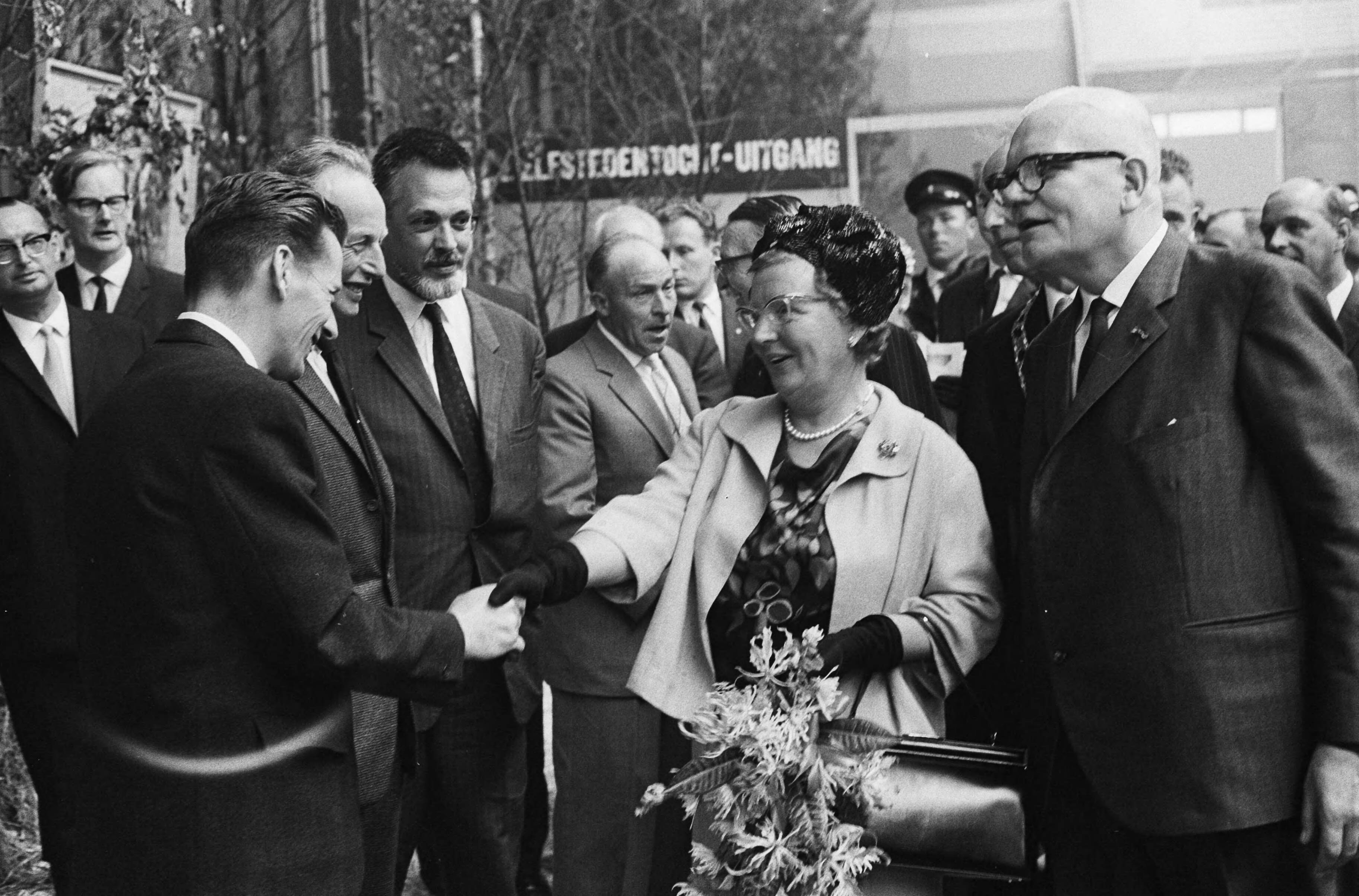 Fotocollectie Anefo — Koningin Juliana bracht een bezoek aan de tentoonstelling "Frisiana" te Leeuwarden. De vorstin wordt voorgesteld aan winnaars van de Elfstedentocht en schudt de hand van Jeen van den Berg, de winnaar van 1954, naast hem Sipke Castelein, winnaar in 1933, daarnaast de schilder Cees Bantzinger, waarvan een tentoonstelling van Elfstedentochtschilderijen te zien is, in de achtergrond de derde winnaar Auke Adema (1940 en 1941). Rechts J.L. Hoogland, voorzitter van de vereniging De Friese Elf Steden — Foto: Pot, Harry / Anefo. Licentie: Set B: Rechtenvrij / Publiek Domein. Bron: Nationaal Archief. http://hdl.handle.net/10648/aa45dcda-d0b4-102d-bcf8-003048976d84