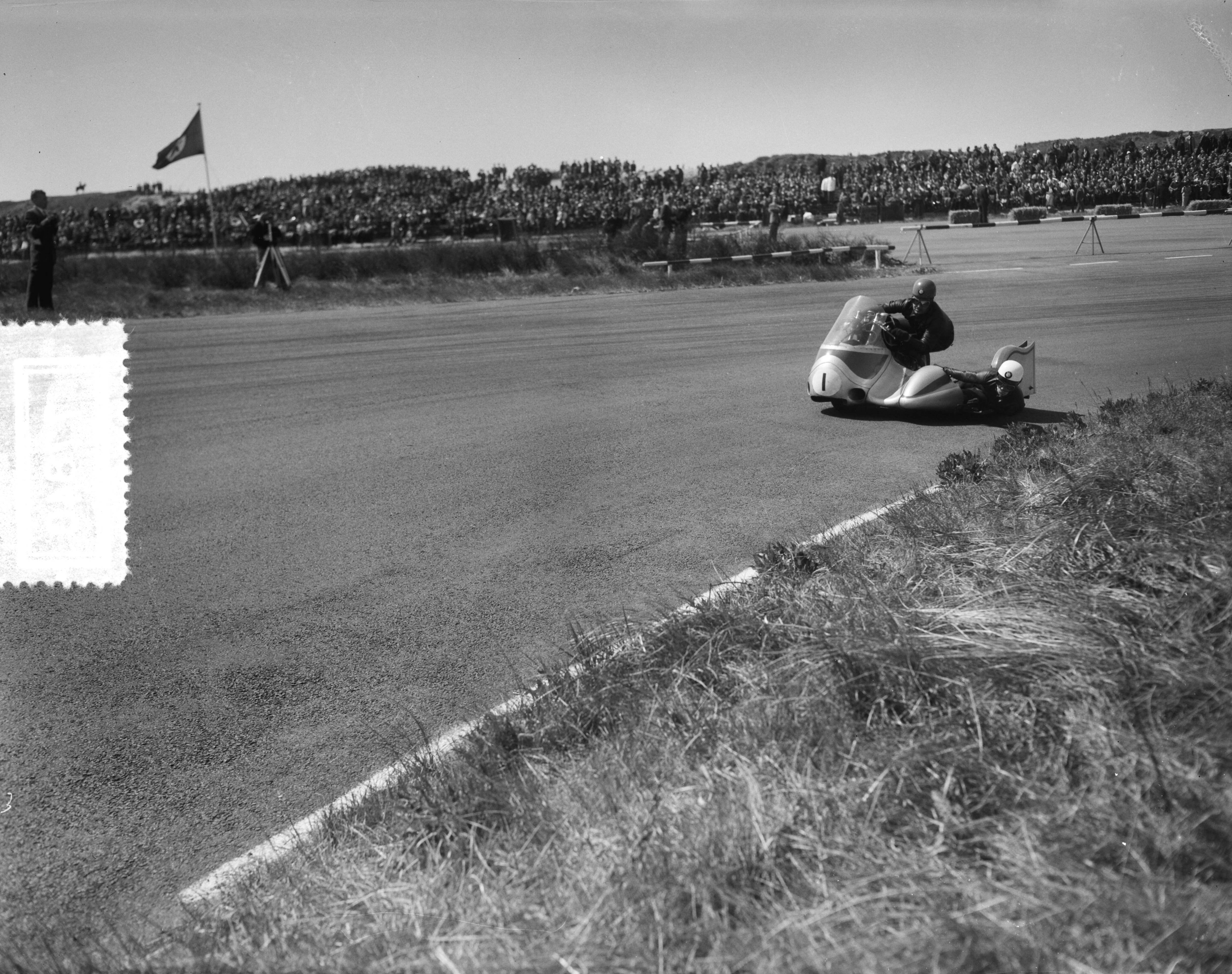 Fotocollectie Anefo — Zijspanrace op het circuit van Zandvoort. Jacques Drion (met bakkeniste Ingeborg Stoll) (Frankrijk/Duitsland) — Foto: Bilsen, Joop van / Anefo. Licentie: Set B: Rechtenvrij / Publiek Domein. Bron: Nationaal Archief. http://hdl.handle.net/10648/a948a1f0-d0b4-102d-bcf8-003048976d84