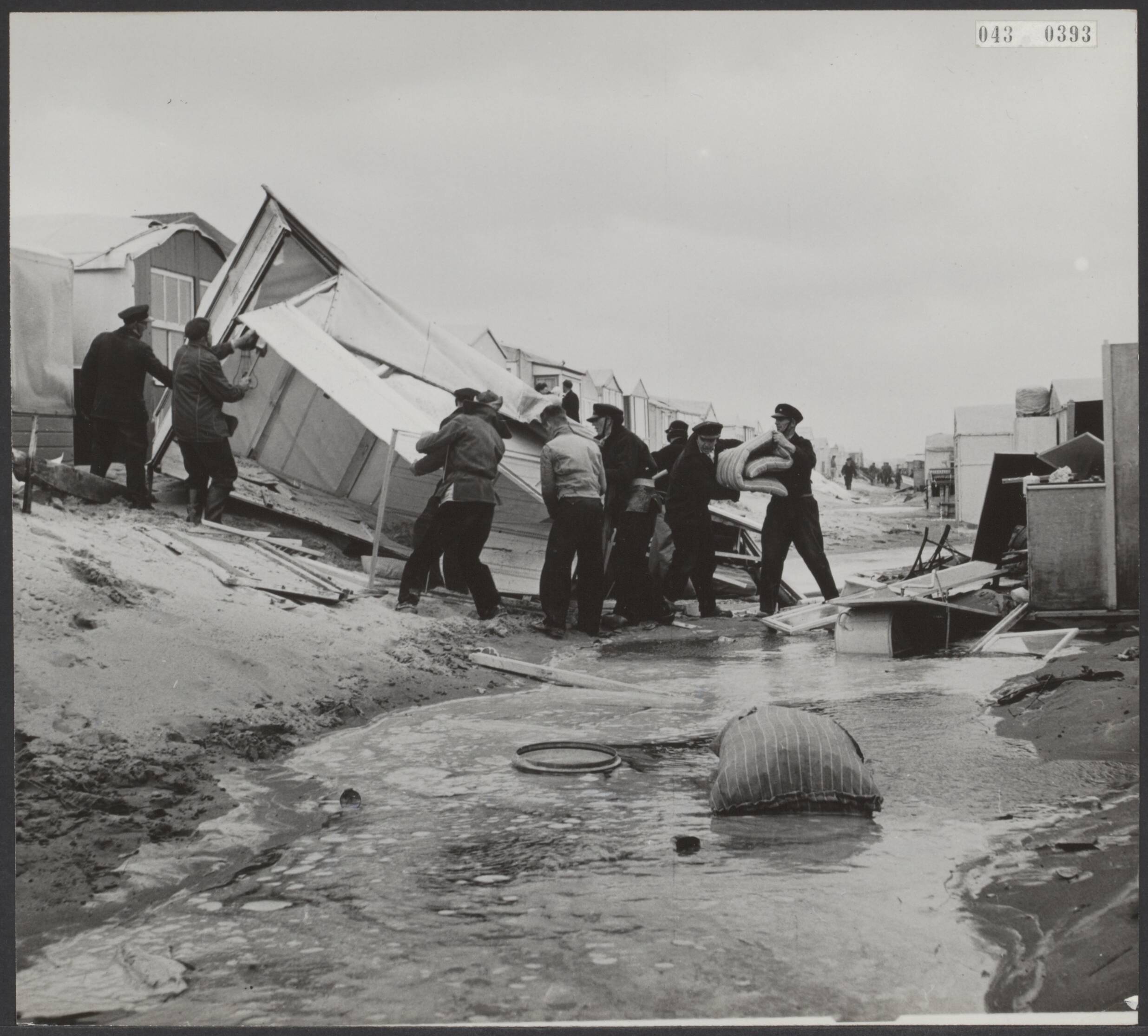 Fotocollectie Elsevier Binnenland — De storm heeft in Zandvoort grote schade aan de kampeerhuisjes aan het strand veroorzaakt. Op het kampeerterein "Helios" werden ca. 15 tenthuisjes vernield. Politie en mensen van Publieke WErken hielpen met het opruimen — Foto: Fotograaf Onbekend / Anefo. Licentie: Set B: Rechtenvrij / Publiek Domein. Bron: Nationaal Archief. http://hdl.handle.net/10648/adf8dc92-d0b4-102d-bcf8-003048976d84