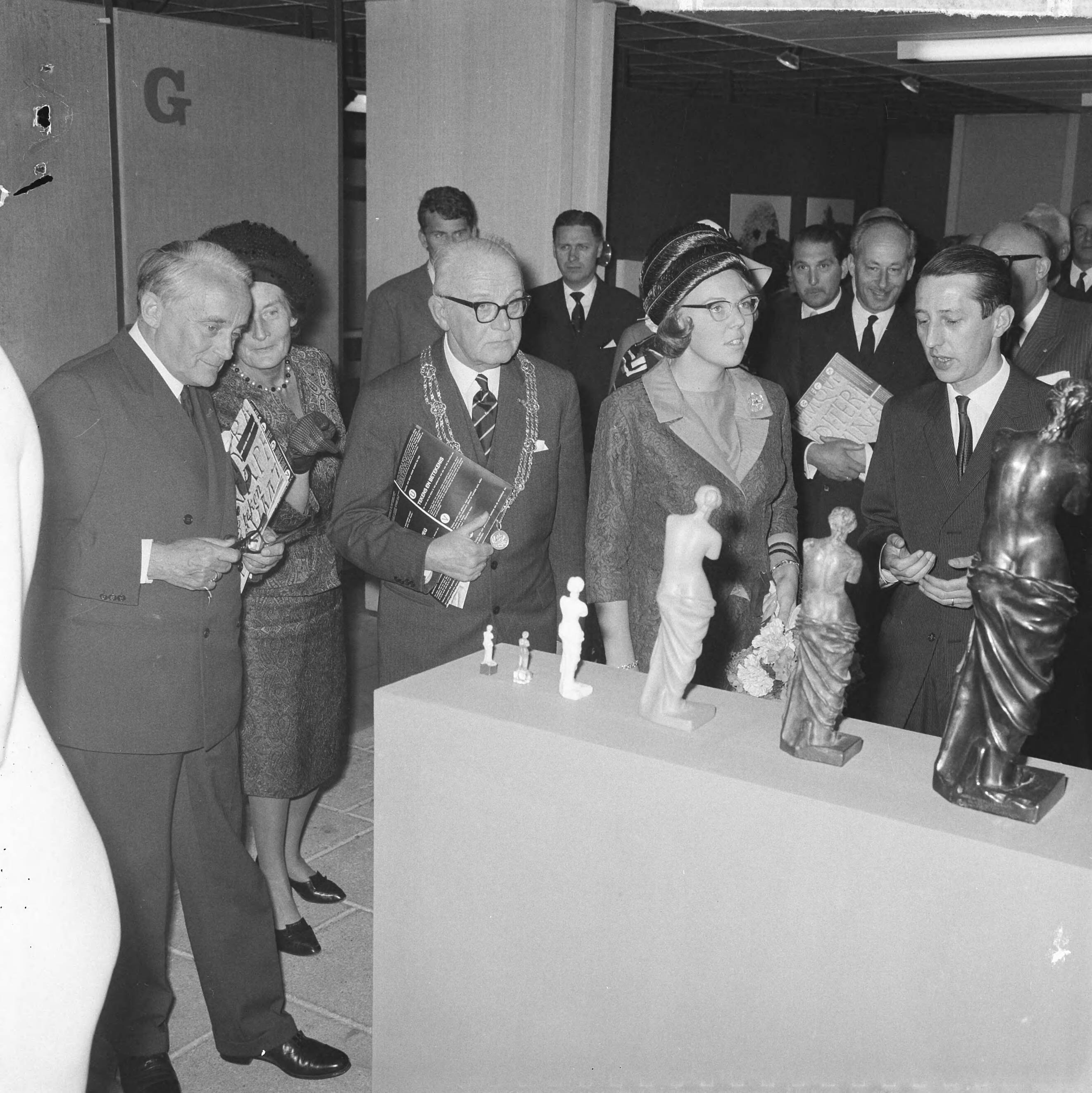 Fotocollectie Anefo — Prinses Beatrix woonde de opening bij van de tentoonstelling "Taal en Teken" in het Gemeentemuseum Den Haag. Prinses Beatrix tijdens de rondgang met de Commissaris der Koningin in Zuid-Holland, mr. J. Klaasesz (links) en burgemeester Kolfschoten — Foto: Nijs, Jac. de / Anefo. Licentie: Set B: Rechtenvrij / Publiek Domein. Bron: Nationaal Archief. http://hdl.handle.net/10648/aaa5bc18-d0b4-102d-bcf8-003048976d84