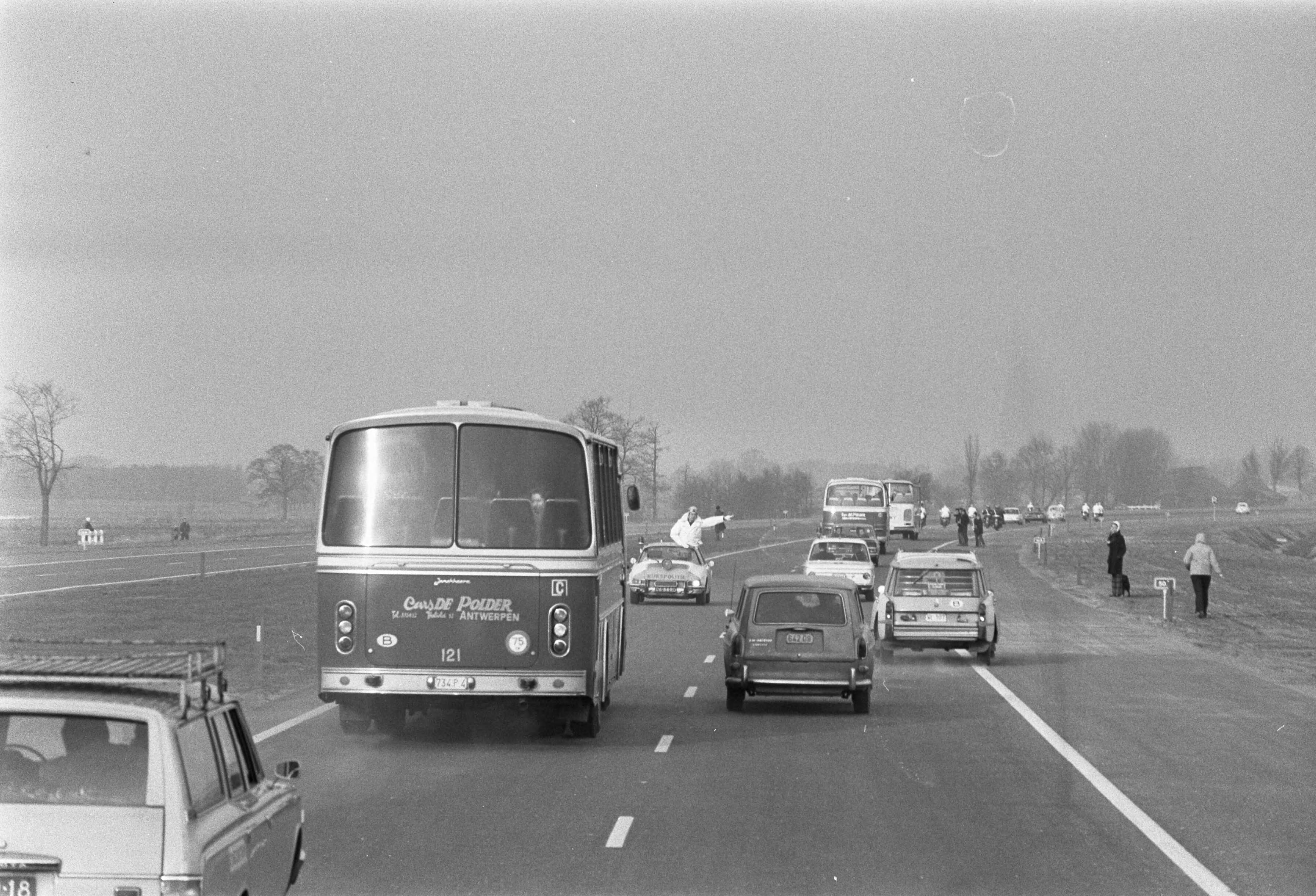 Opening van de E10, de nieuwe snelweg tussen Breda en Antwerpen, door — De bus met daarin koningin Juliana en koning Boudewijn op de nieuwe weg — Foto: Fotograaf Onbekend / Anefo. Licentie: Set B: Rechtenvrij / Publiek Domein. Bron: Nationaal Archief. http://hdl.handle.net/10648/abde624c-d0b4-102d-bcf8-003048976d84
