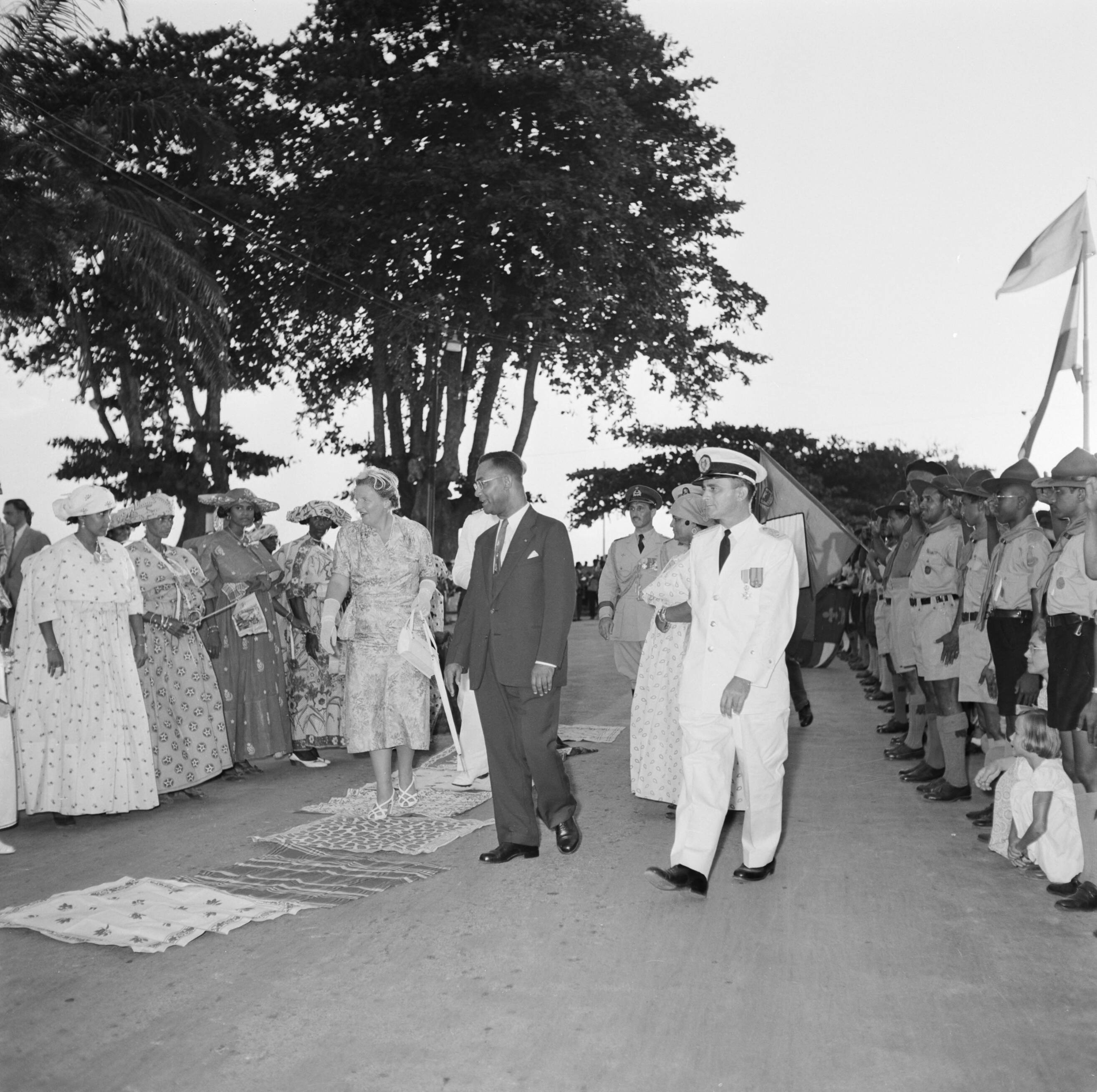 Nederlandse Antillen en Suriname ten tijde van het koninklijk bezoek van koningin Juliana en prins Bernhard in 1955 — Koningin en prins lopen door Dumburg. Rechts gouverneur Klaasesz en Johan Ferrier, voorzitter van de ministerraad — Foto: Poll, Willem van de. Licentie: Set B: Rechtenvrij / Publiek Domein. Bron: Nationaal Archief. http://hdl.handle.net/10648/aeb26c84-d0b4-102d-bcf8-003048976d84