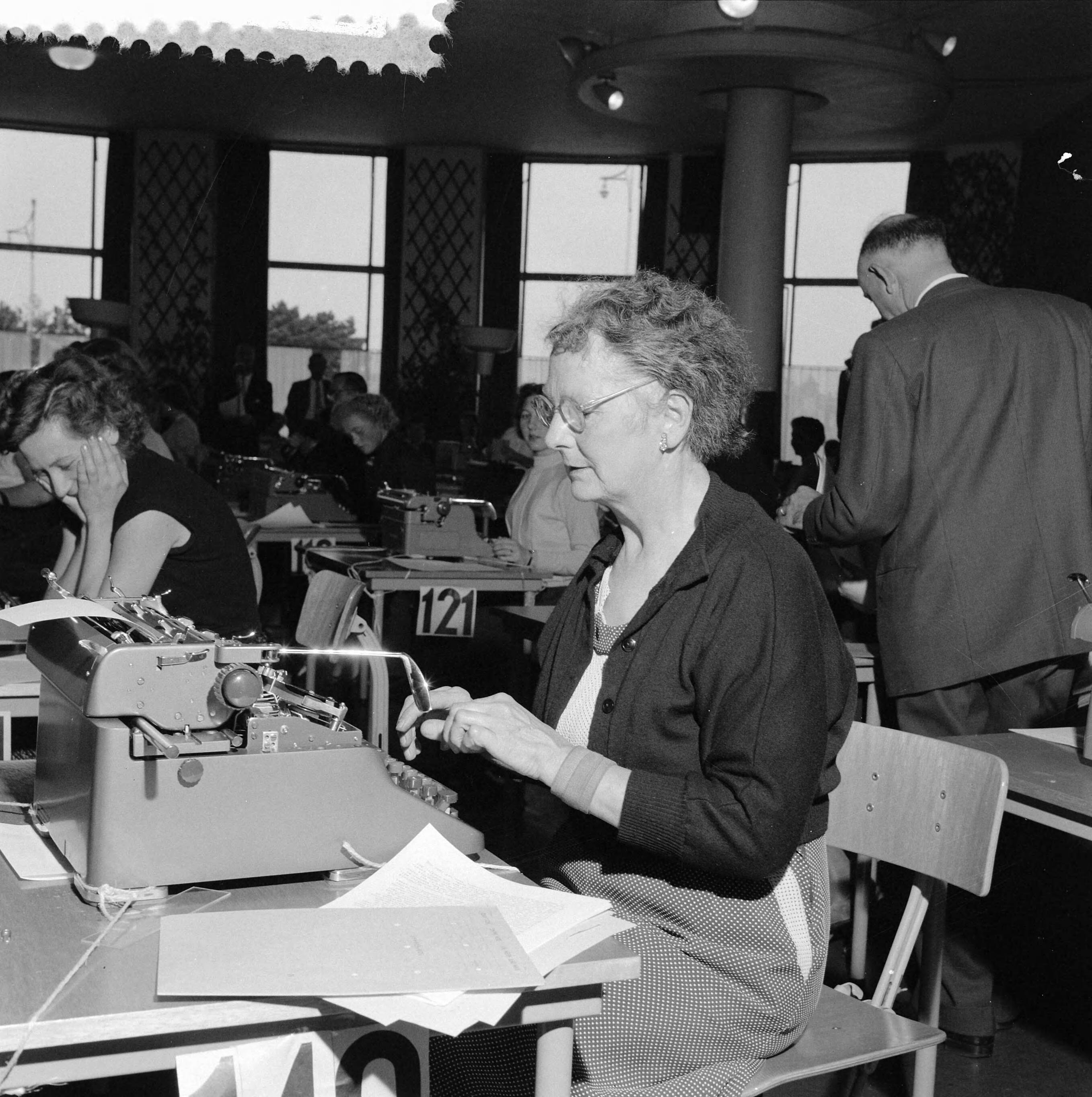 Fotocollectie Anefo — Kampioenschap machineschrijven in de Houtrusthal in Den Haag — Foto: Behrens, Herbert F. / Anefo. Licentie: Set B: Rechtenvrij / Publiek Domein. Bron: Nationaal Archief. http://hdl.handle.net/10648/a96b2be4-d0b4-102d-bcf8-003048976d84