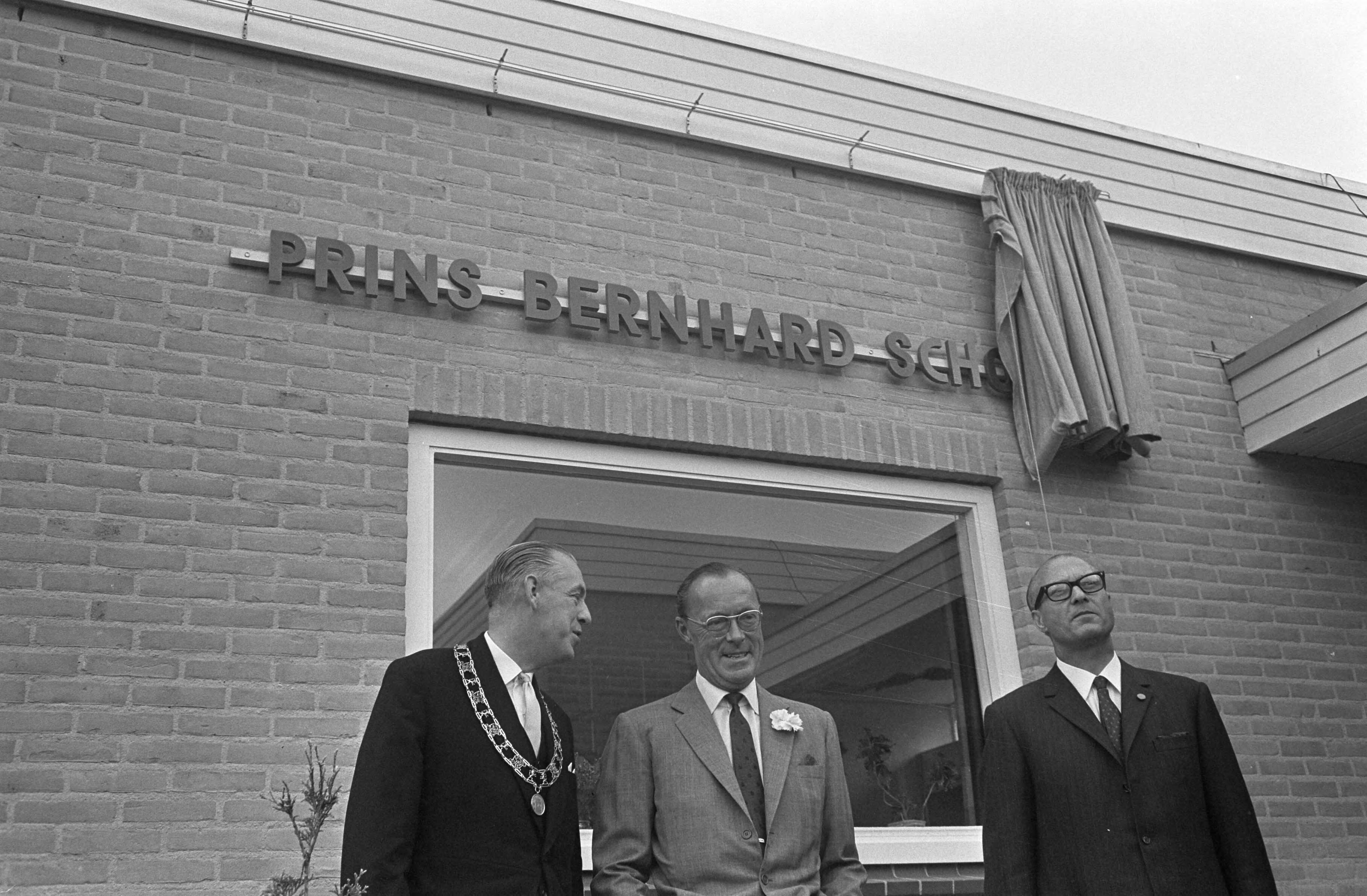 Prins Bernhard opent de Prins Bernhard school te Leeuwarden — De prins en de burgemeester staan voor de zojuist onthulde naam — Foto: Fotograaf Onbekend / Anefo. Licentie: Set B: Rechtenvrij / Publiek Domein. Bron: Nationaal Archief. http://hdl.handle.net/10648/ab4c4876-d0b4-102d-bcf8-003048976d84