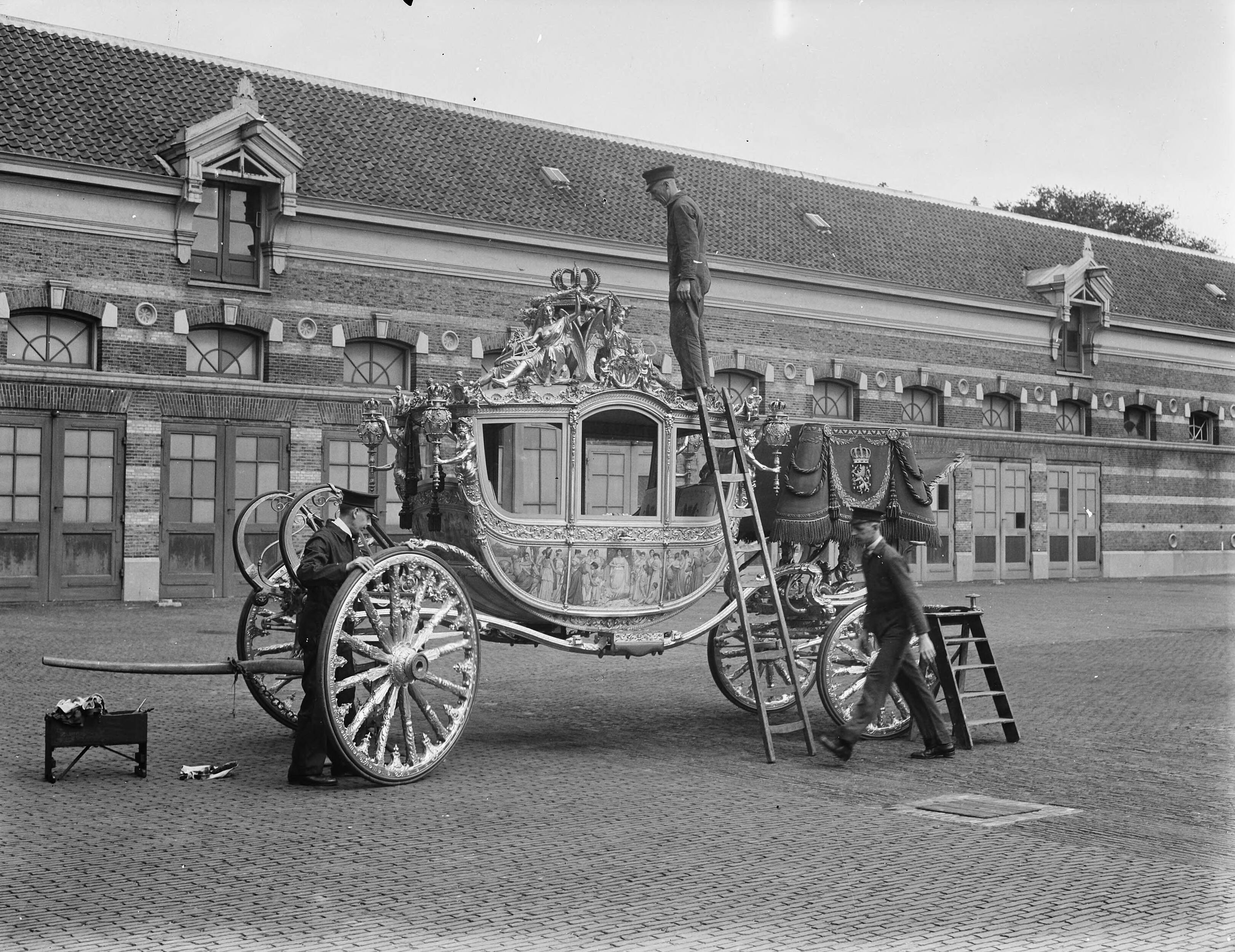 Koninklijke Stallen te Den Haag. Voorbereidingen viering Regeringsjubileum — Koninklijks Stallen te Den Haag. Gouden Koets wordt schoongemaakt — Foto: Merk, Ben / Anefo. Licentie: Set B: Rechtenvrij / Publiek Domein. Bron: Nationaal Archief. http://hdl.handle.net/10648/a8babc1e-d0b4-102d-bcf8-003048976d84
