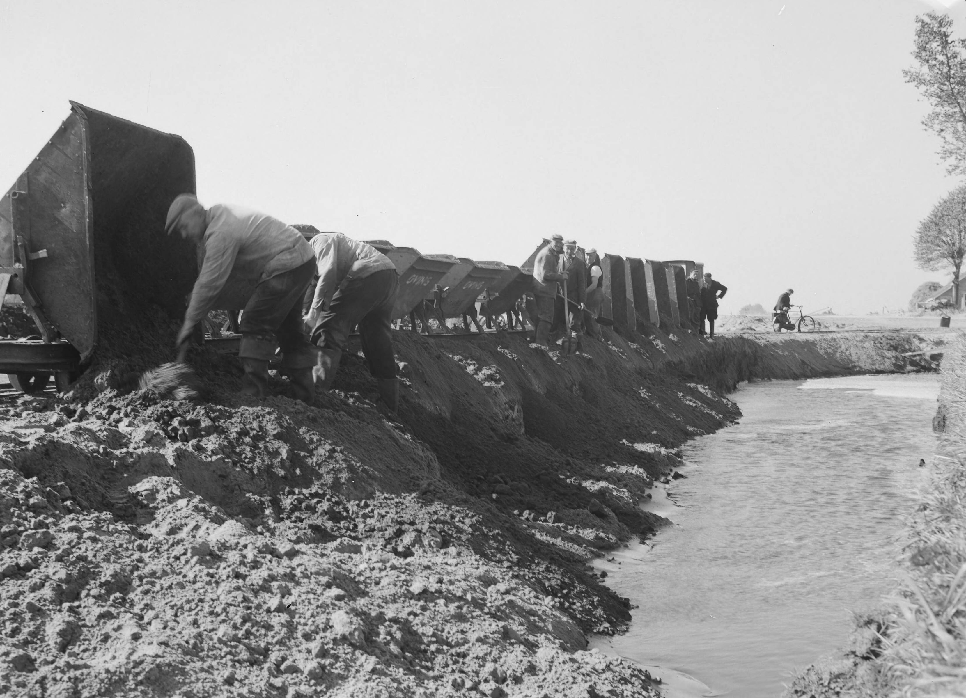 Fotocollectie Nederlandse Heidemaatschappij — Lossen kipkarren bij wegaanleg Slochteren — Foto: Nijhof, [...] / Heidemij. Licentie: Set B: Rechtenvrij / Publiek Domein. Bron: Nationaal Archief. http://hdl.handle.net/10648/ae6f85ea-d0b4-102d-bcf8-003048976d84