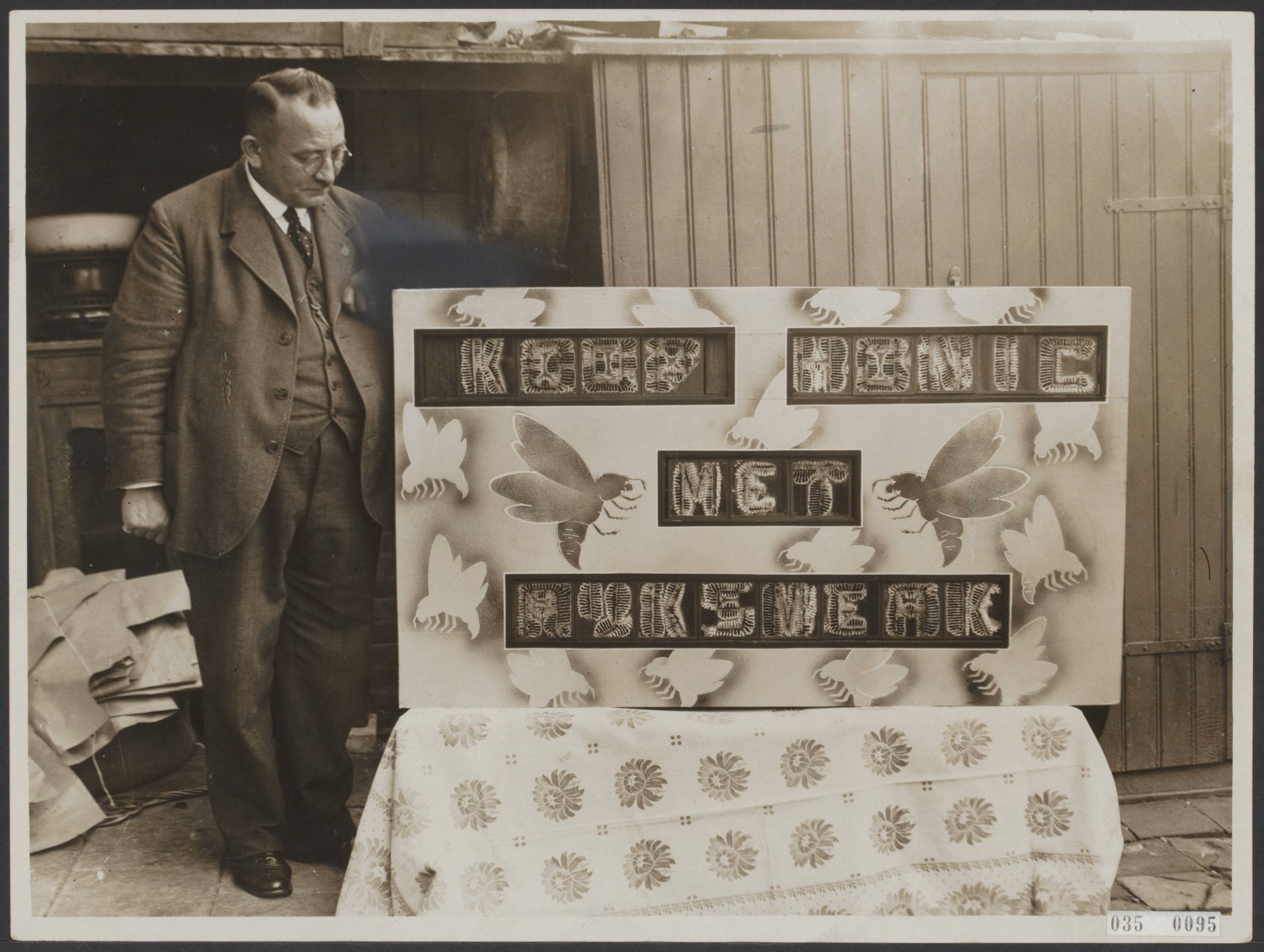 Fotocollectie Elsevier Binnenland — Bijschrift "Schrijvende bijen! De heer S. Frankenhuis te Rijswijk, een van onze bekwaamste imkers, is erin geslaagd, zijn bijen bovenstaande zin [koop honig met ?] van de fijnste raathoning, in glazen bakjes te laten uitbouwen. Een buitengewone prestatie op bijenteeltgebied. De "dresseur" bij het resultaat van zijn nijver volkje" — Foto: N.V. Polygoon. Licentie: Set B: Rechtenvrij / Publiek Domein. Bron: Nationaal Archief. http://hdl.handle.net/10648/ade9ab78-d0b4-102d-bcf8-003048976d84