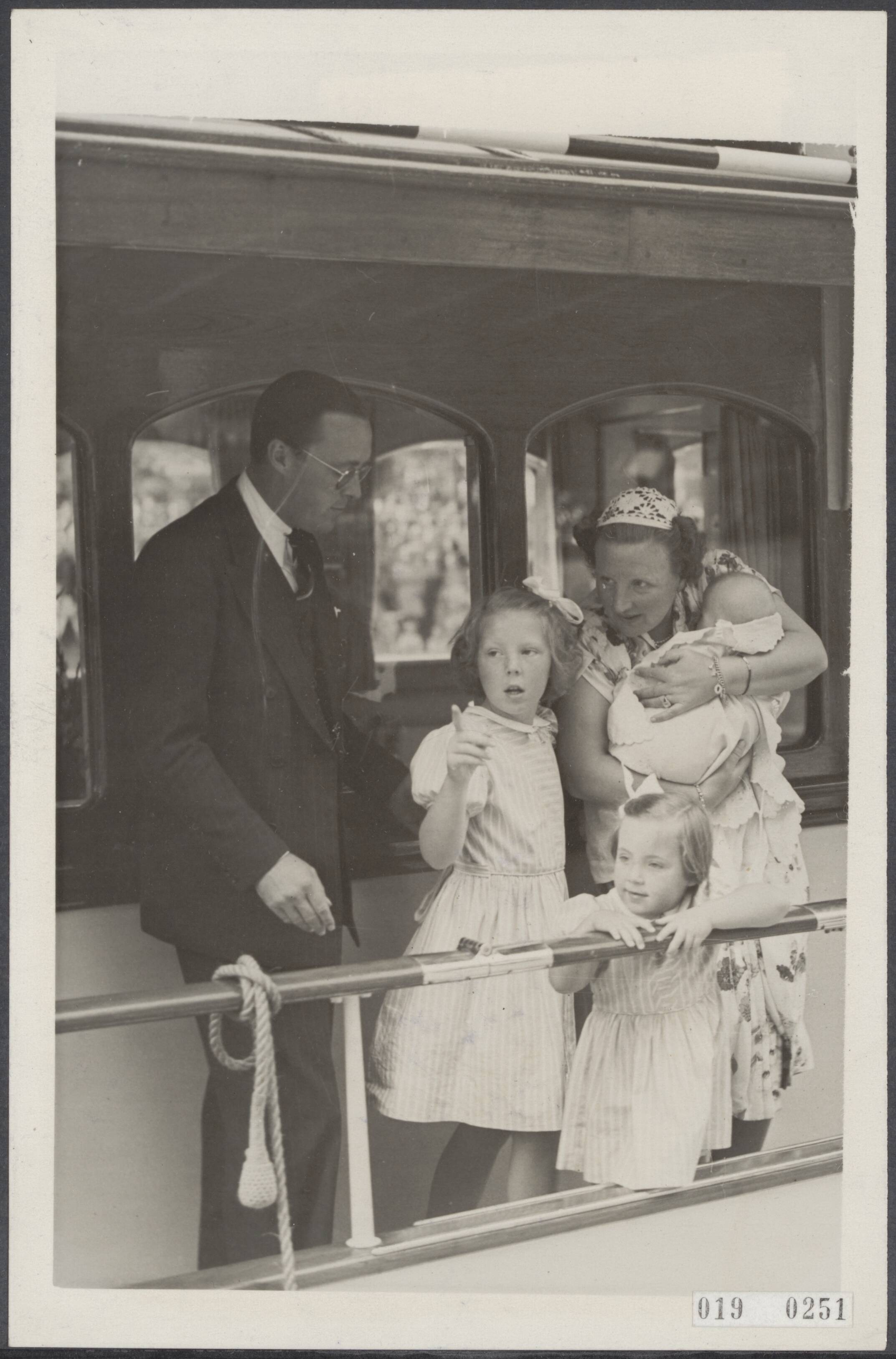 Fotocollectie Elsevier Binnenland — Een enorme ontvangst is het prinselijk paar met de prinsesjes in Leeuwarden ten deel gevallen, vanwaar zij op de "Piet Hein" een vakantietocht door Friesland gaan maken. Bij het vertrek van de "Piet Hein". Prinses Juliana met prinses Marijke (Christina) op de arm. Prins Bernhard en de prinsjesjes Beatrix en Margiert kijken belangstellend naar de grote menige die het prinselijke gezin uitgeleide deed — Foto: ANP / RVD of rechtenvrij. Licentie: Set B: Rechtenvrij / Publiek Domein. Bron: Nationaal Archief. http://hdl.handle.net/10648/adc5f2fa-d0b4-102d-bcf8-003048976d84
