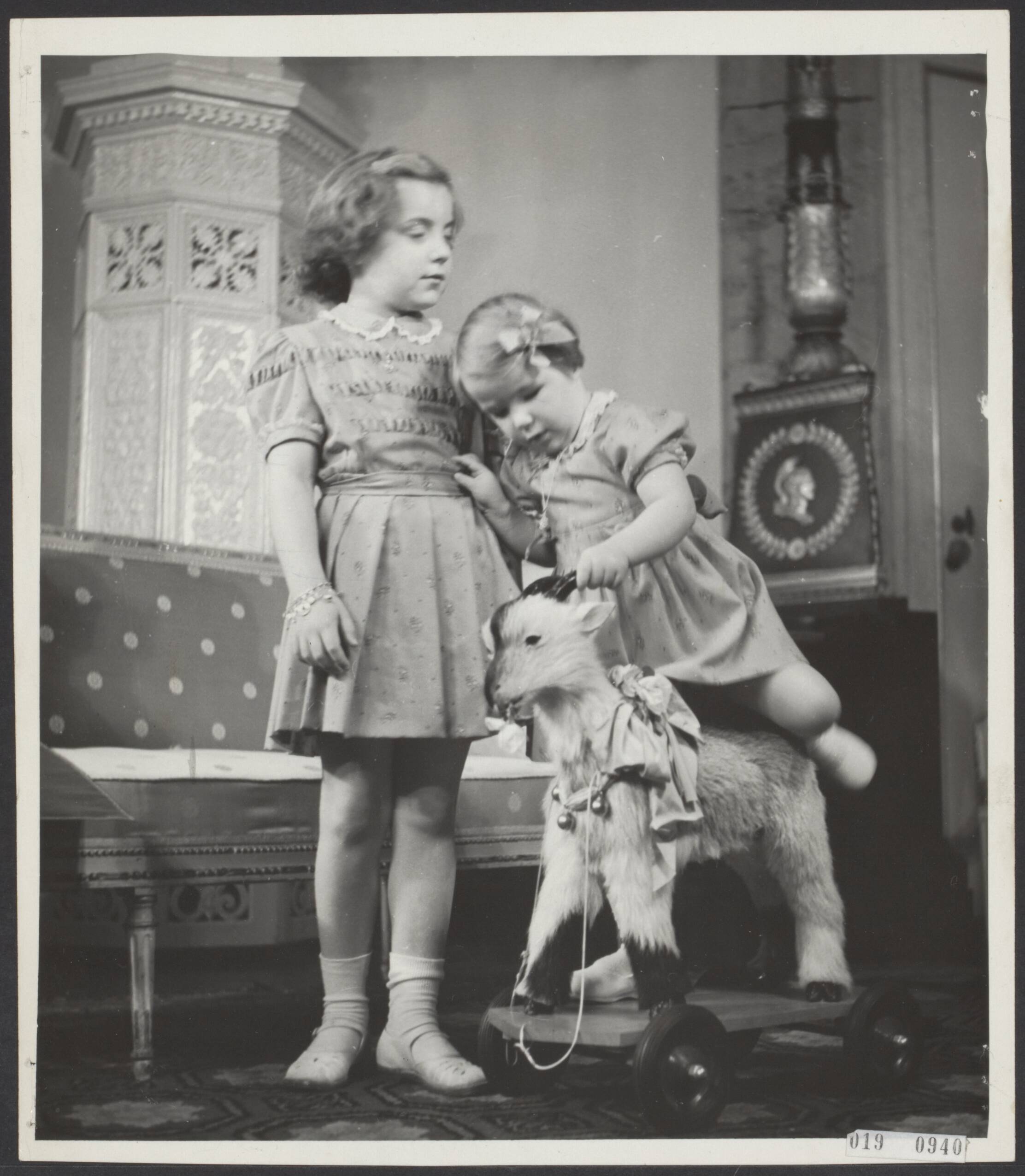 Fotocollectie Elsevier Binnenland — In de Stuczaal van paleis Soestdijk gaat prinses Marijke (Christina ) op een speelgoed-geitje zitten. Naast haar staat prinses Margriet — Foto: Fotograaf Onbekend / Anefo. Licentie: Set B: Rechtenvrij / Publiek Domein. Bron: Nationaal Archief. http://hdl.handle.net/10648/adc82192-d0b4-102d-bcf8-003048976d84