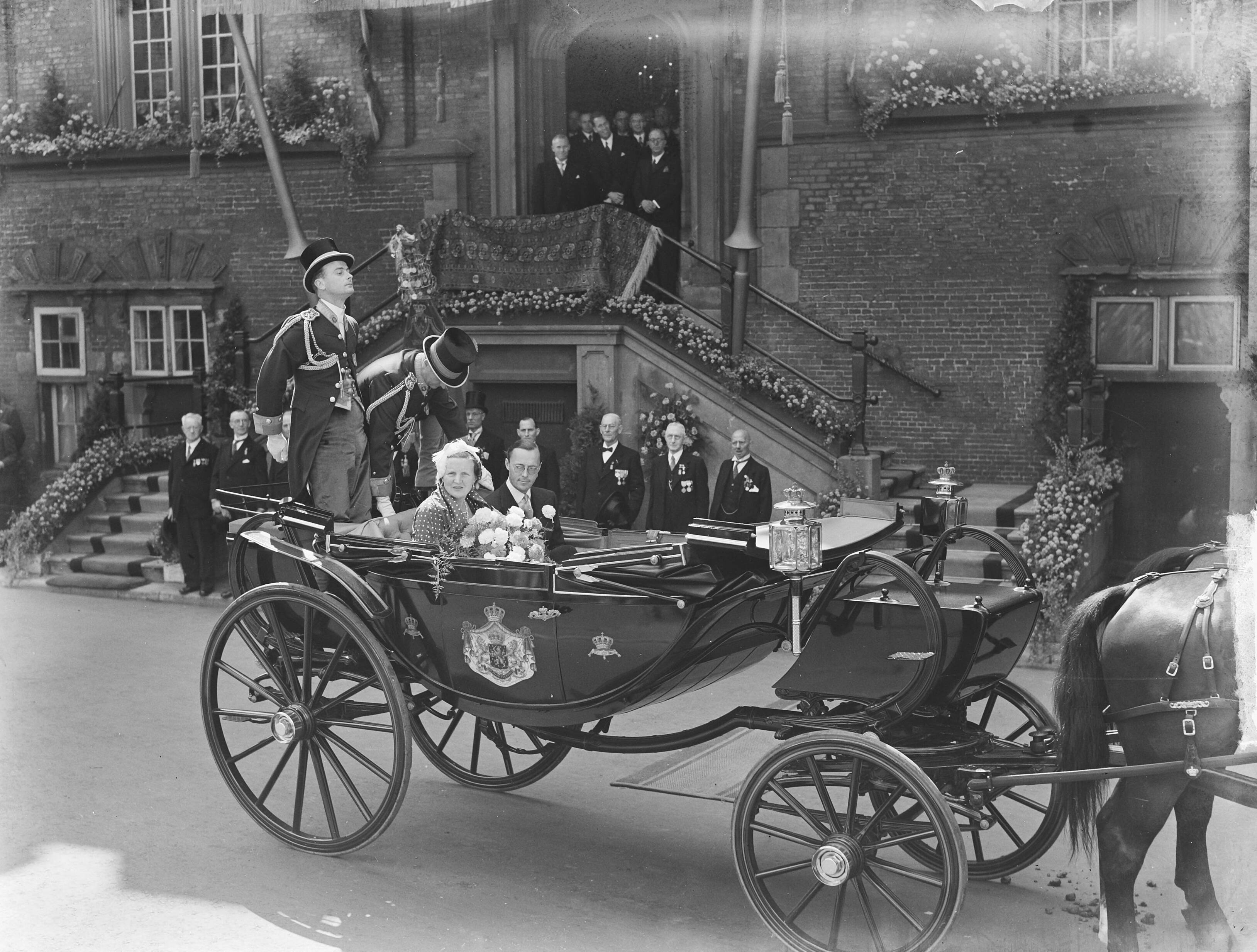 Koningin Juliana en prins Bernhard in Haarlem — Rijtoer met het koninklijk paar in de koets voor het stadhuis — Foto: Bilsen, Joop van / Anefo. Licentie: Set B: Rechtenvrij / Publiek Domein. Bron: Nationaal Archief. http://hdl.handle.net/10648/a8cb2c34-d0b4-102d-bcf8-003048976d84