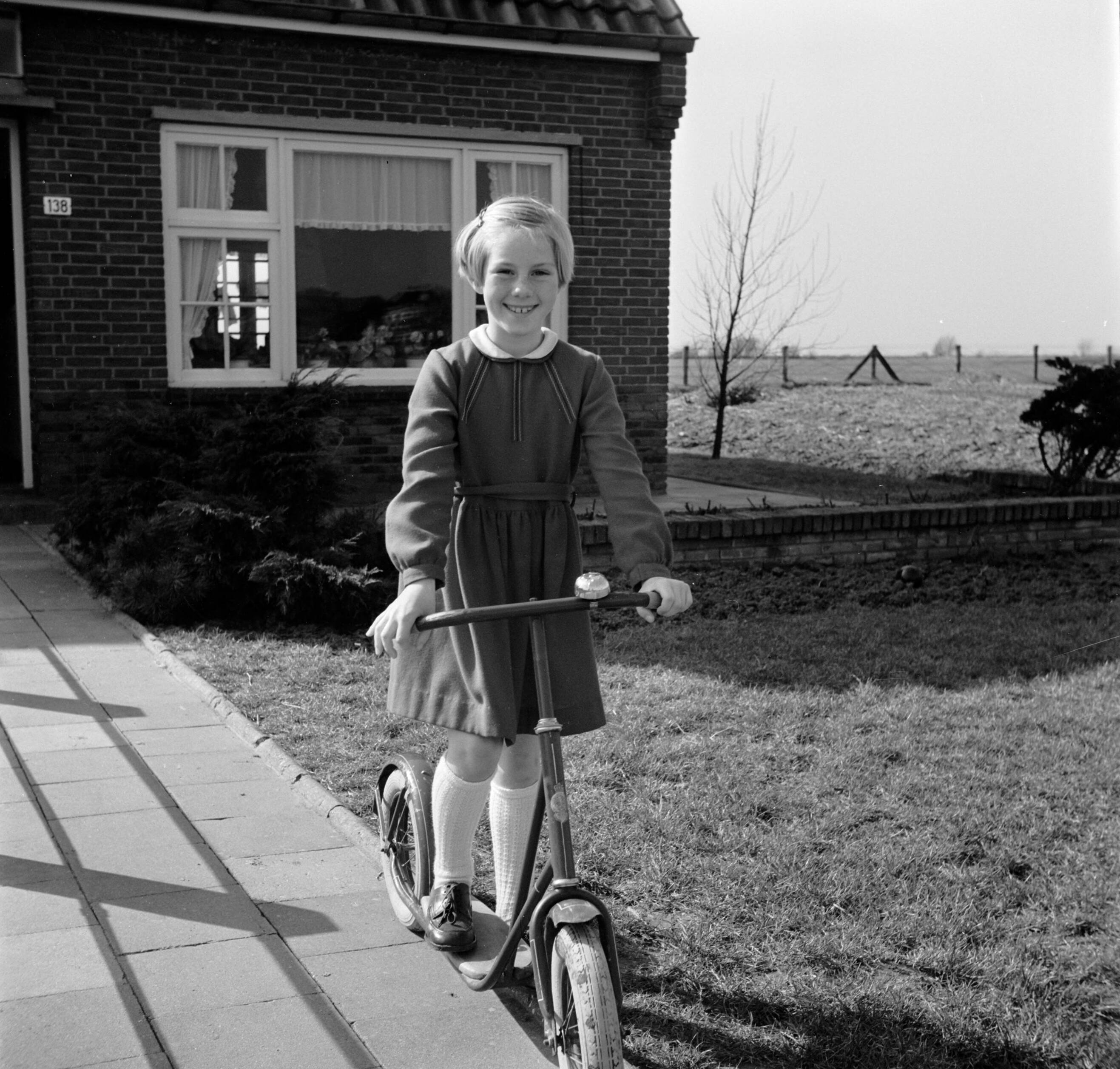 Fotocollectie Van de Poll — Marietje, de achtjarige dochter van Gerard, op haar autoped in de voortuin — Foto: Poll, Willem van de. Licentie: Set B: Rechtenvrij / Publiek Domein. Bron: Nationaal Archief. http://hdl.handle.net/10648/aecccd04-d0b4-102d-bcf8-003048976d84