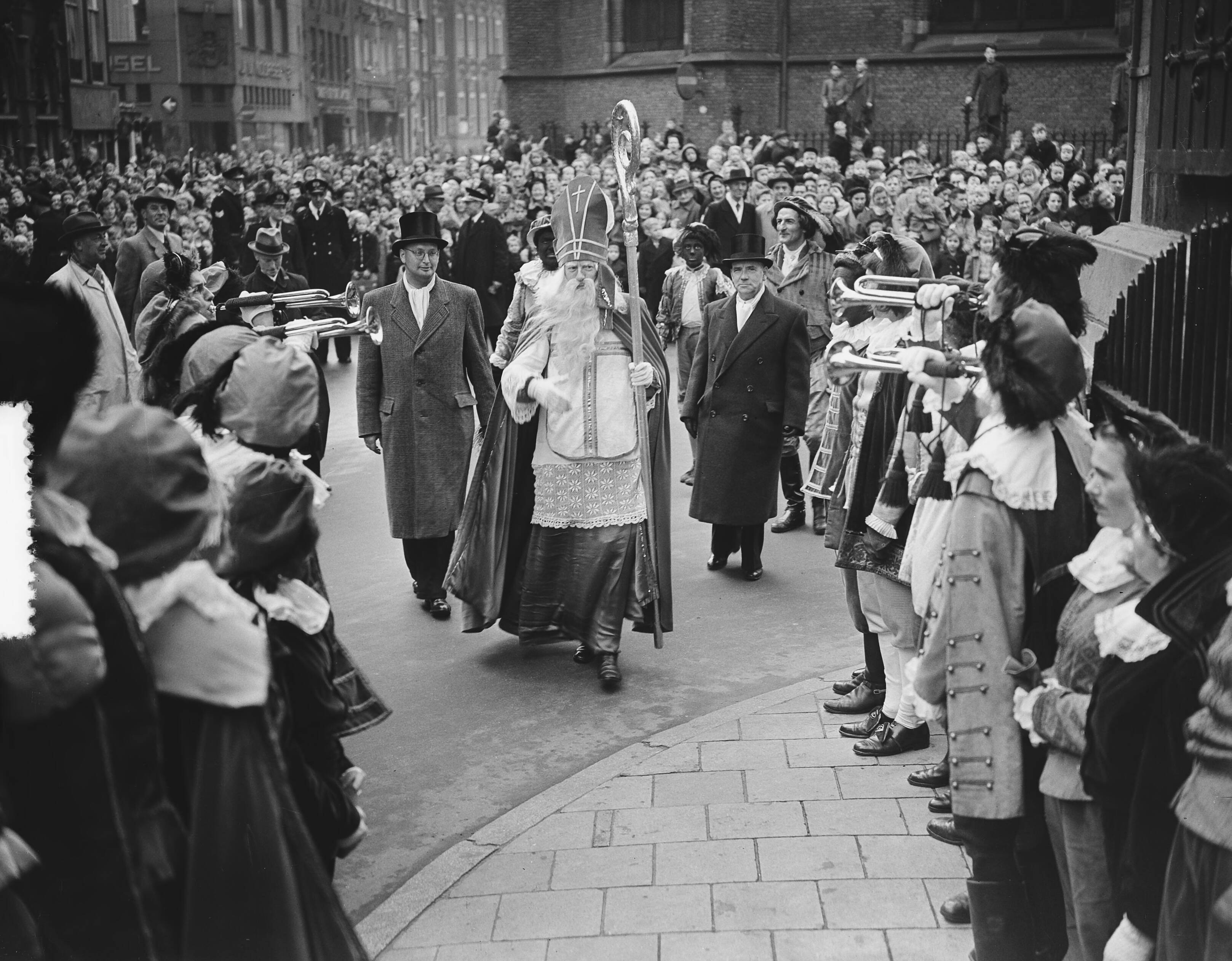 Intocht Sint-Nicolaas te Den Haag (1951) — Intocht van Sint Nicolaas te Den Haag. Op de Groenmarkt — Foto: Bilsen, Joop van / Anefo. Licentie: Set B: Rechtenvrij / Publiek Domein. Bron: Nationaal Archief. http://hdl.handle.net/10648/a8f22820-d0b4-102d-bcf8-003048976d84