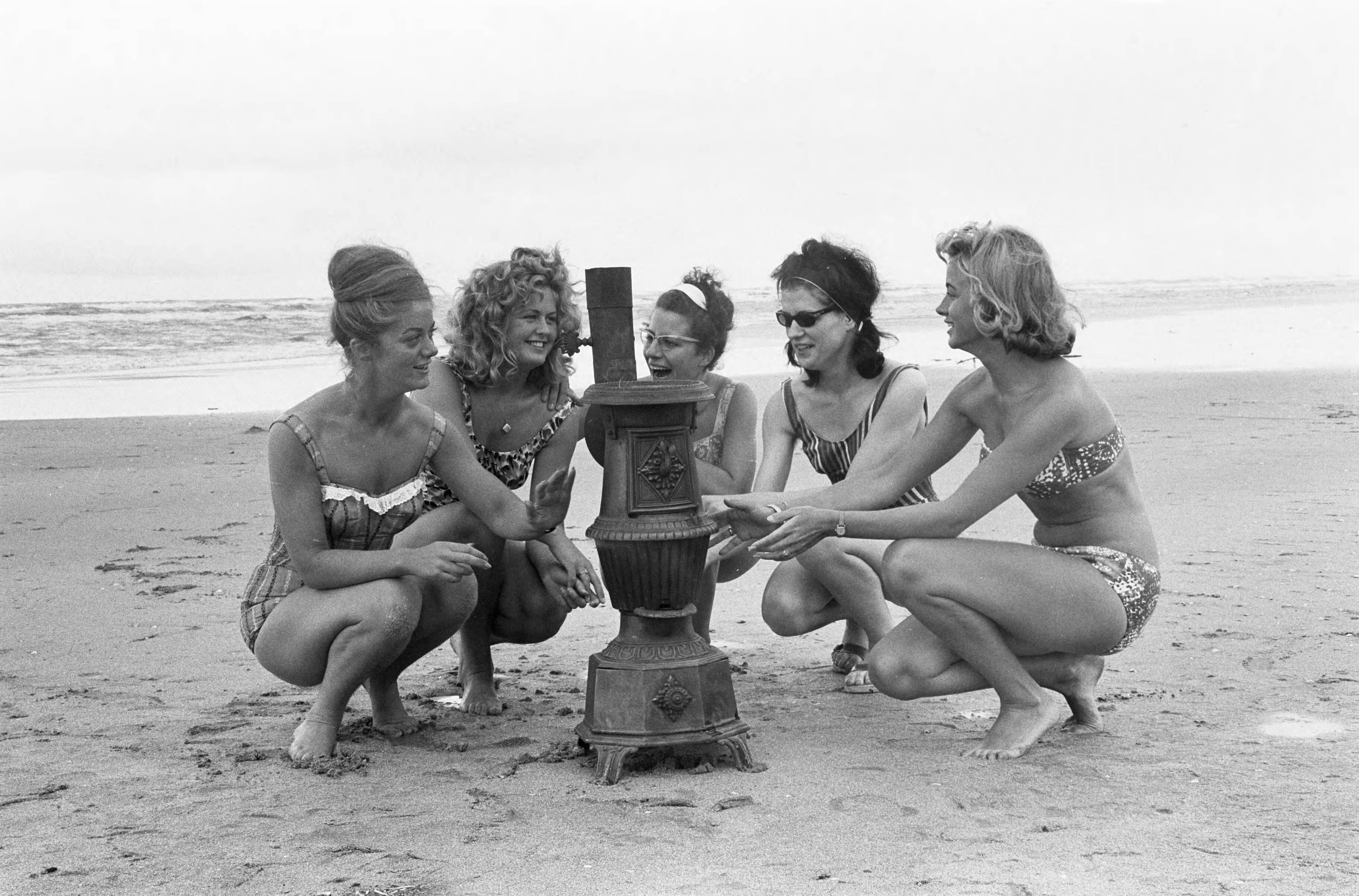 Fotocollectie Anefo — Slecht weer strand Zandvoort. Vijf vrouwelijke optimisten rond een kachel op het strand — Foto: Pot, Harry / Anefo. Licentie: Set B: Rechtenvrij / Publiek Domein. Bron: Nationaal Archief. http://hdl.handle.net/10648/aa0f5e8a-d0b4-102d-bcf8-003048976d84