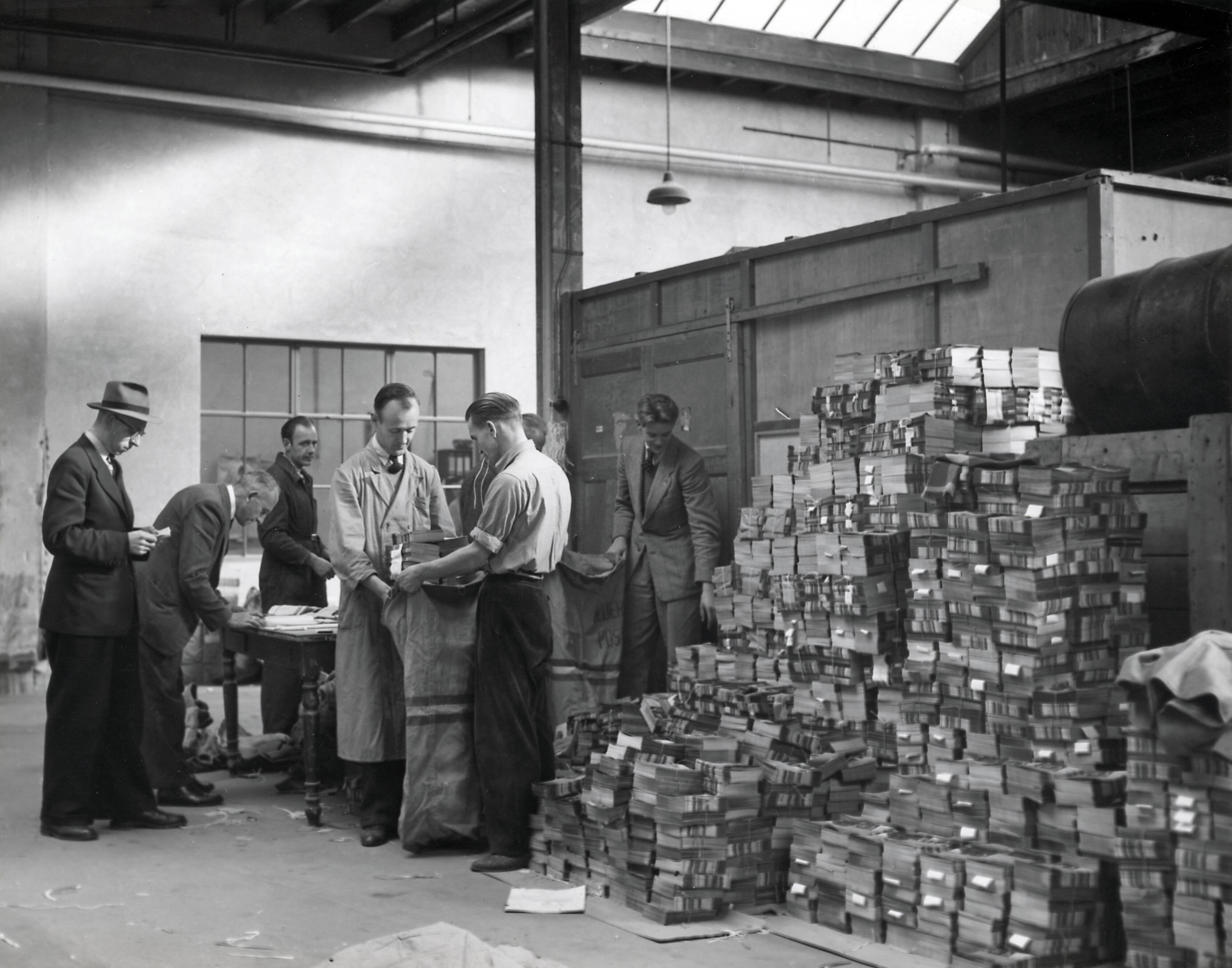 Collectie nader te bepalen — [Serie Bedrijfsvoering Spaarnestad] [tijdschriften worden in postzakken gestopt in een expeditieruimte] — Foto: Fotograaf Onbekend / Fotobureau onbekend / Spaarnestad Photo (05887). Licentie: Set B: Rechtenvrij / Publiek Domein. Bron: Nationaal Archief. http://hdl.handle.net/10648/35429da6-4297-a382-e063-6df0900a6686