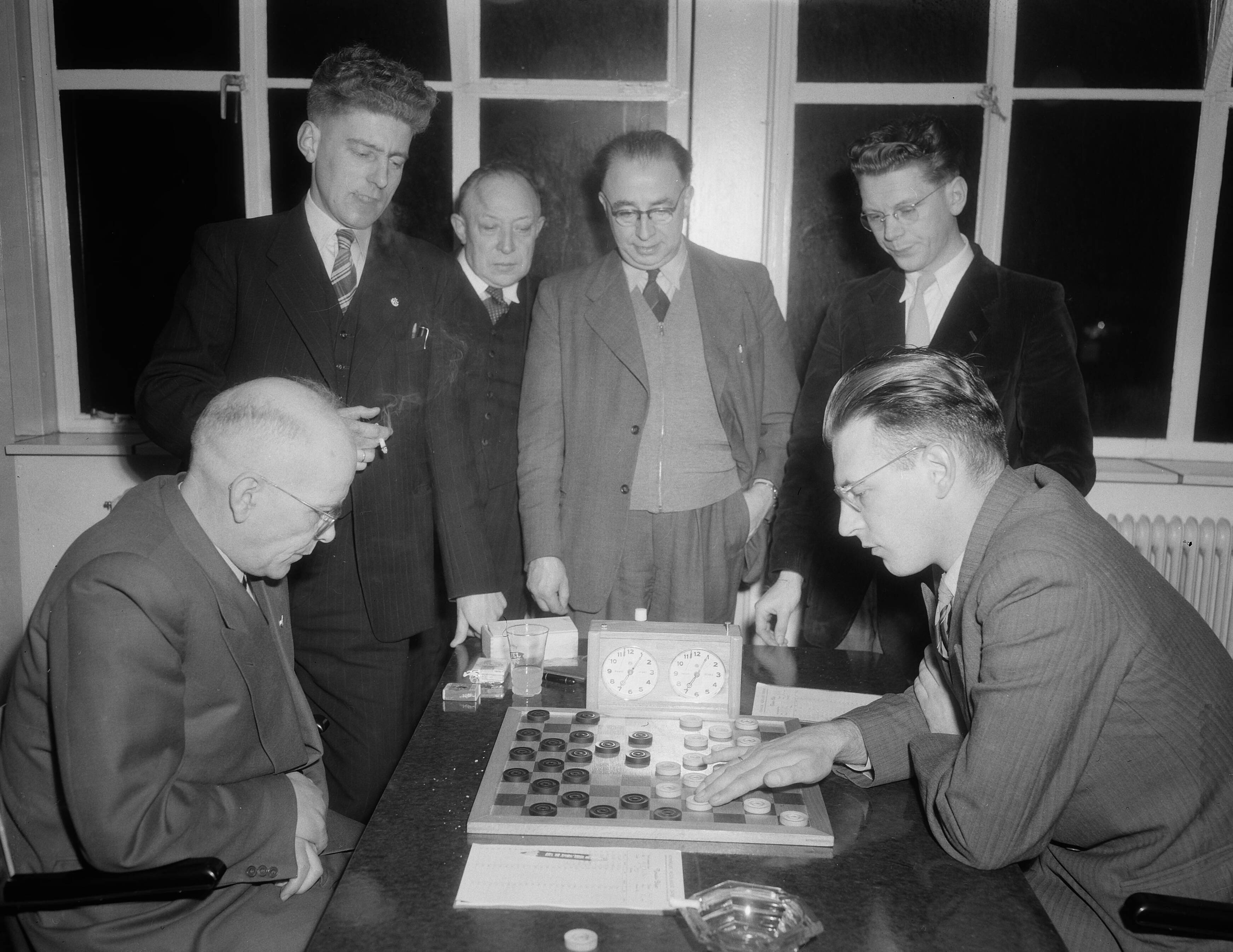Fotocollectie Anefo — Nederlands kampioenschap Dammen in Utrecht. A. Jurg (Overijssel) tegen Ir. Van Dijk (Gelderland). Achter de tafel vlnr. A. v.d. Berg (2e Zuid-Holland), de wedstrijdleider van de Utrechtse Provinciale Dam Bond, de wedstrijdleider van de Kon. Ned. Dam Bond en J.H. Ansems (kampioen van Noord-Holland) — Foto: Duinen, G.W. van / Anefo. Licentie: Set B: Rechtenvrij / Publiek Domein. Bron: Nationaal Archief. http://hdl.handle.net/10648/a91da702-d0b4-102d-bcf8-003048976d84