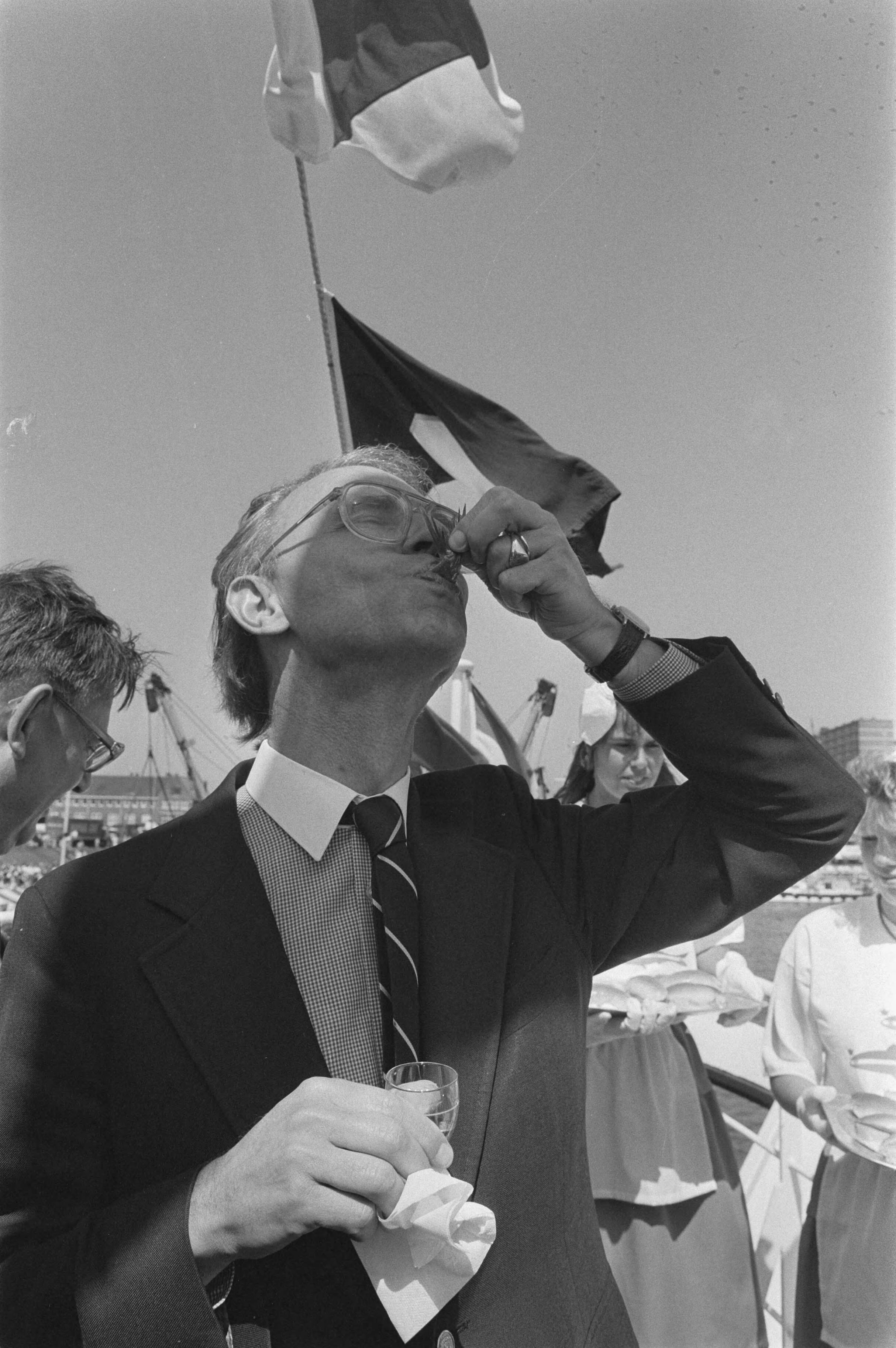 Fotocollectie Anefo — Traditionele Vlaggetjesdag in Scheveningen aan begin haringvangst; minister Ruding met haring — Foto: Croes, Rob C. / Anefo. Licentie: Set B: Rechtenvrij / Publiek Domein. Bron: Nationaal Archief. http://hdl.handle.net/10648/ad539a70-d0b4-102d-bcf8-003048976d84