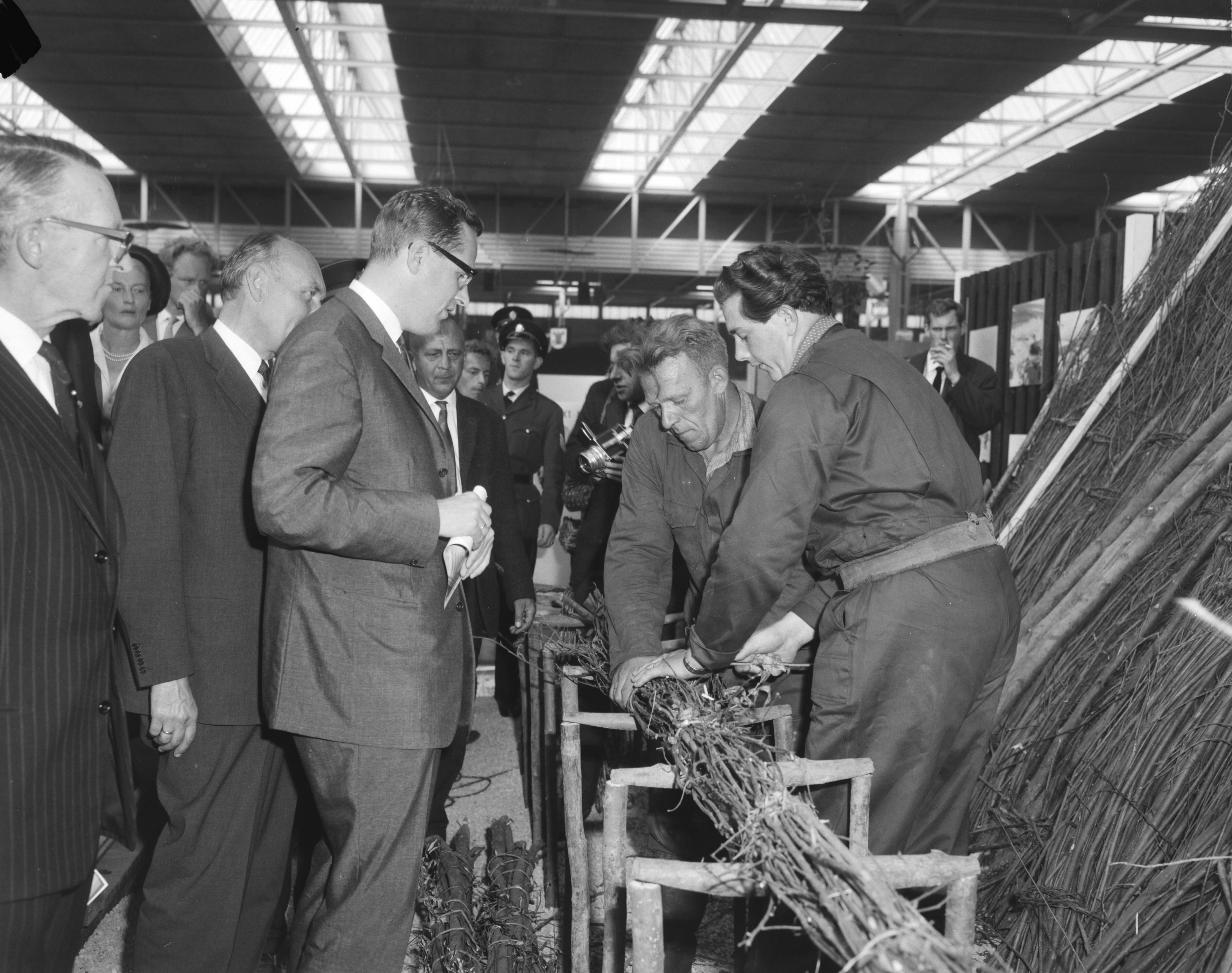 Fotocollectie Anefo — Tentoonstelling "Frisiana" te Leeuwarden officieel door minister J.E. Andriessen geopend. Minister Andriessen tijdens de rondgang. HIj bekijkt de werkzaamheden van rijswerkers — Foto: Bilsen, Joop van / Anefo. Licentie: Set B: Rechtenvrij / Publiek Domein. Bron: Nationaal Archief. http://hdl.handle.net/10648/aa4587e4-d0b4-102d-bcf8-003048976d84