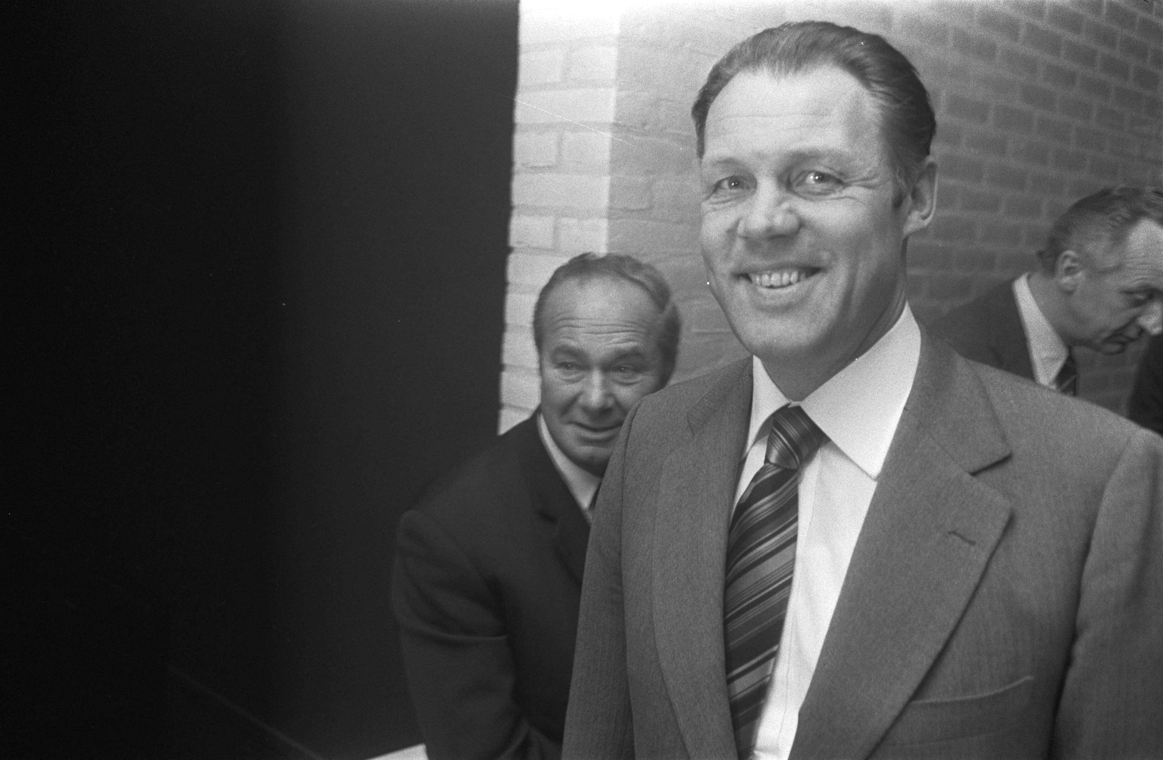 Rinus Michels, supervisor van het Nederlands elftal bij het WK voetbal in 1974 geeft een persconferentie in het KNVB-centrum te Zeist — Michels met achter hem (l) Fadrhonc — Foto: Fotograaf Onbekend / Anefo. Licentie: Set B: Rechtenvrij / Publiek Domein. Bron: Nationaal Archief. http://hdl.handle.net/10648/ac42ccb4-d0b4-102d-bcf8-003048976d84