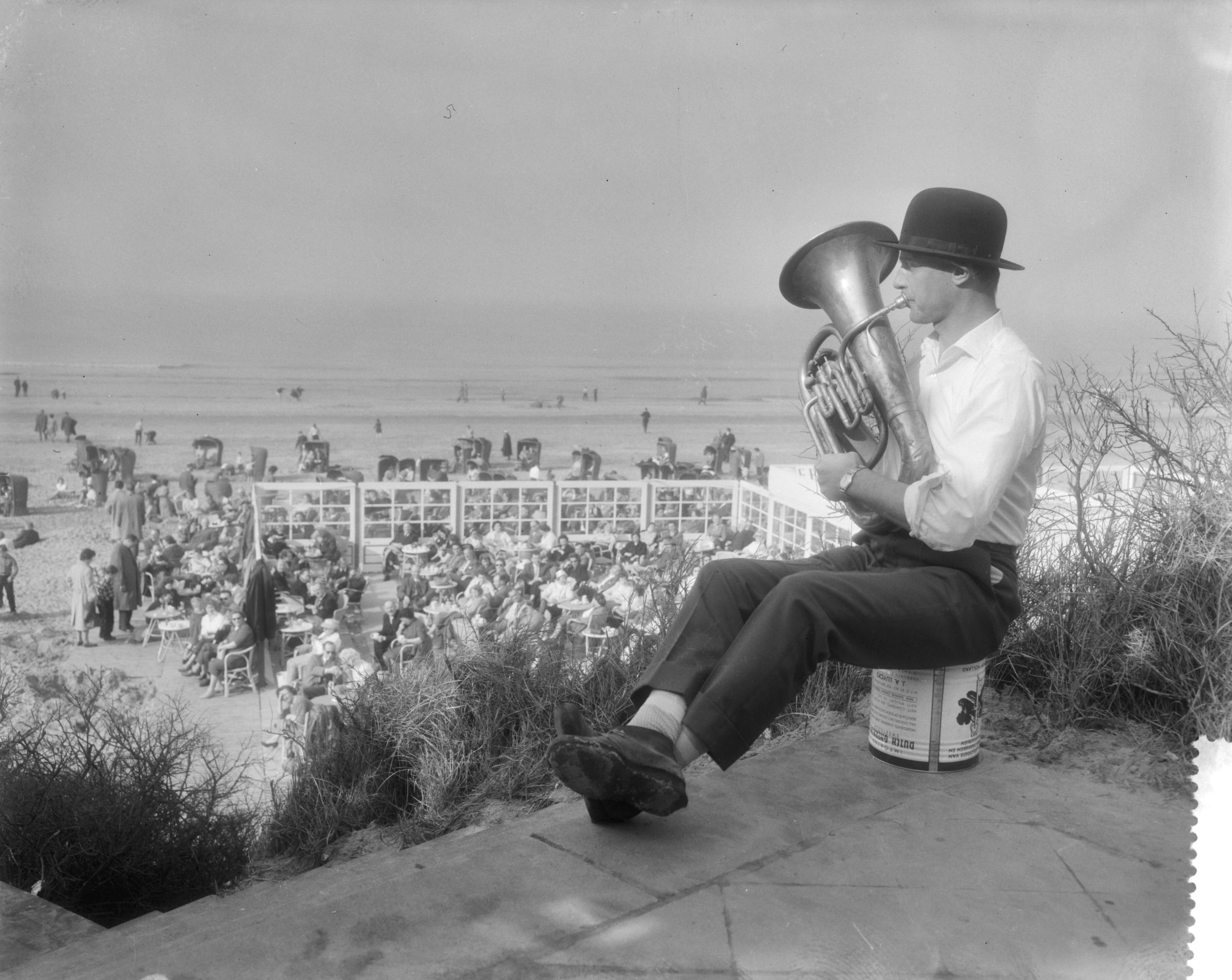 Fotocollectie Anefo — Drukte aan het strand te Zandvoort i.v.m. het mooie weer. Muzikant met tuba en bolhoed — Foto: Pot, Harry / Anefo. Licentie: Set B: Rechtenvrij / Publiek Domein. Bron: Nationaal Archief. http://hdl.handle.net/10648/a98eb046-d0b4-102d-bcf8-003048976d84