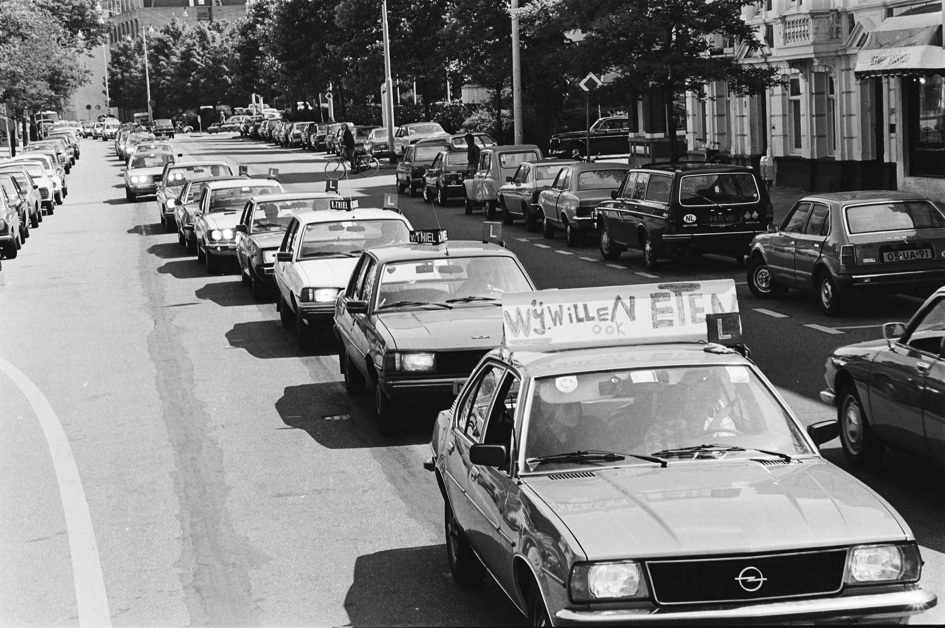 Demonstratie met lesauto's in Den Haag voor verhoging van de maximale lesgelden — Den Haag|Zuid-Holland|betogingen |lesgelden |auto's — Foto: Dijk, Hans van / Anefo. Licentie: Set B: Rechtenvrij / Publiek Domein. Bron: Nationaal Archief. http://hdl.handle.net/10648/accd0064-d0b4-102d-bcf8-003048976d84