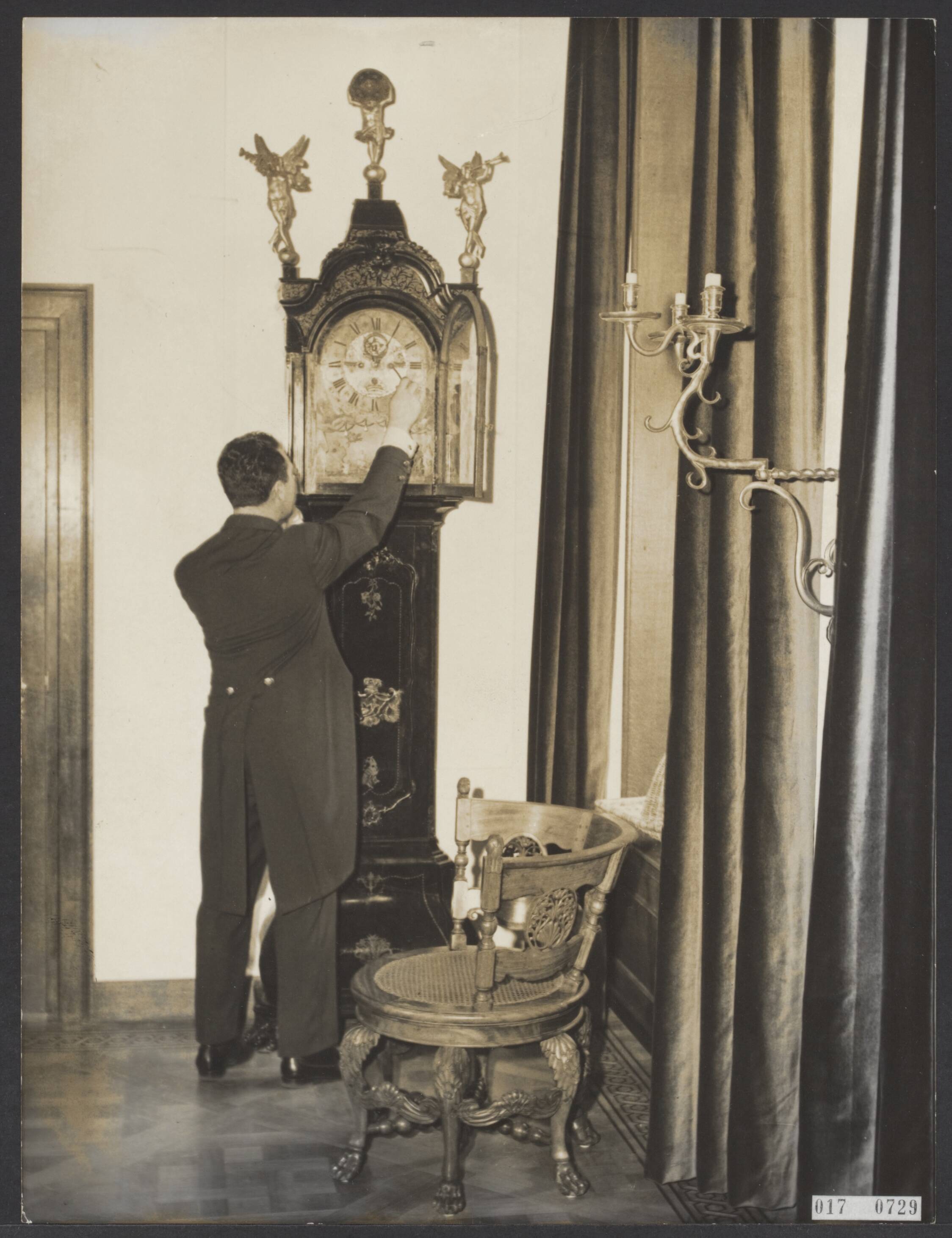 Fotocollectie Elsevier Binnenland — Serie: kasteel Drakensteyn bewoond door prinses Beatrix. Een lakei stelt de wijzerplaat van een staande klok bij — Foto: ANP / RVD of rechtenvrij. Licentie: Set B: Rechtenvrij / Publiek Domein. Bron: Nationaal Archief. http://hdl.handle.net/10648/adbed2b8-d0b4-102d-bcf8-003048976d84