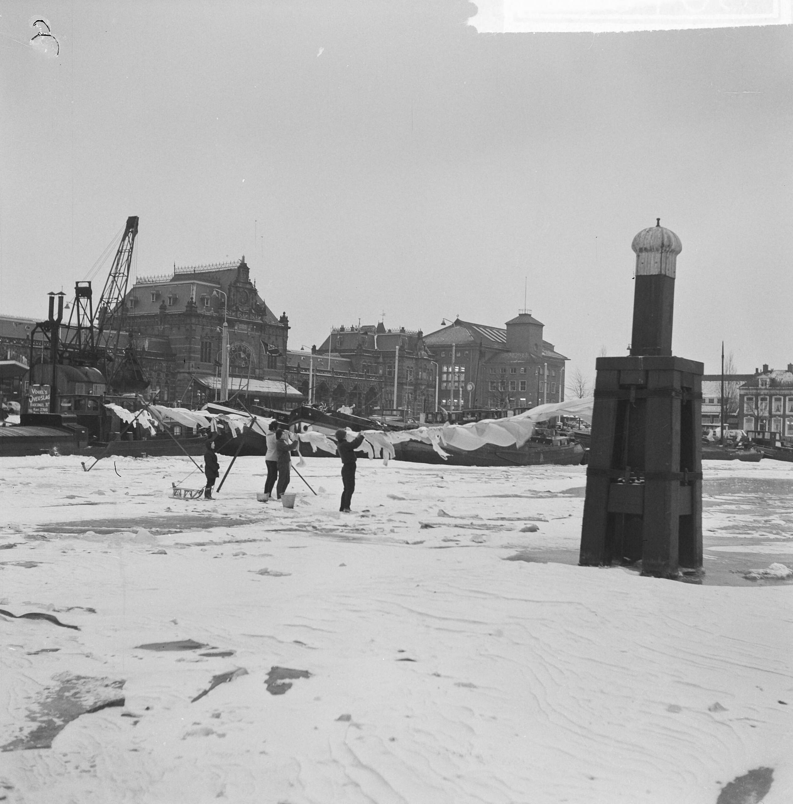 Fotocollectie Anefo — De was hangt op het dichtgevroren Verbindingskanaal te Groningen — Foto: Nijs, Jac. de / Anefo. Licentie: Set B: Rechtenvrij / Publiek Domein. Bron: Nationaal Archief. http://hdl.handle.net/10648/aa24d7ba-d0b4-102d-bcf8-003048976d84