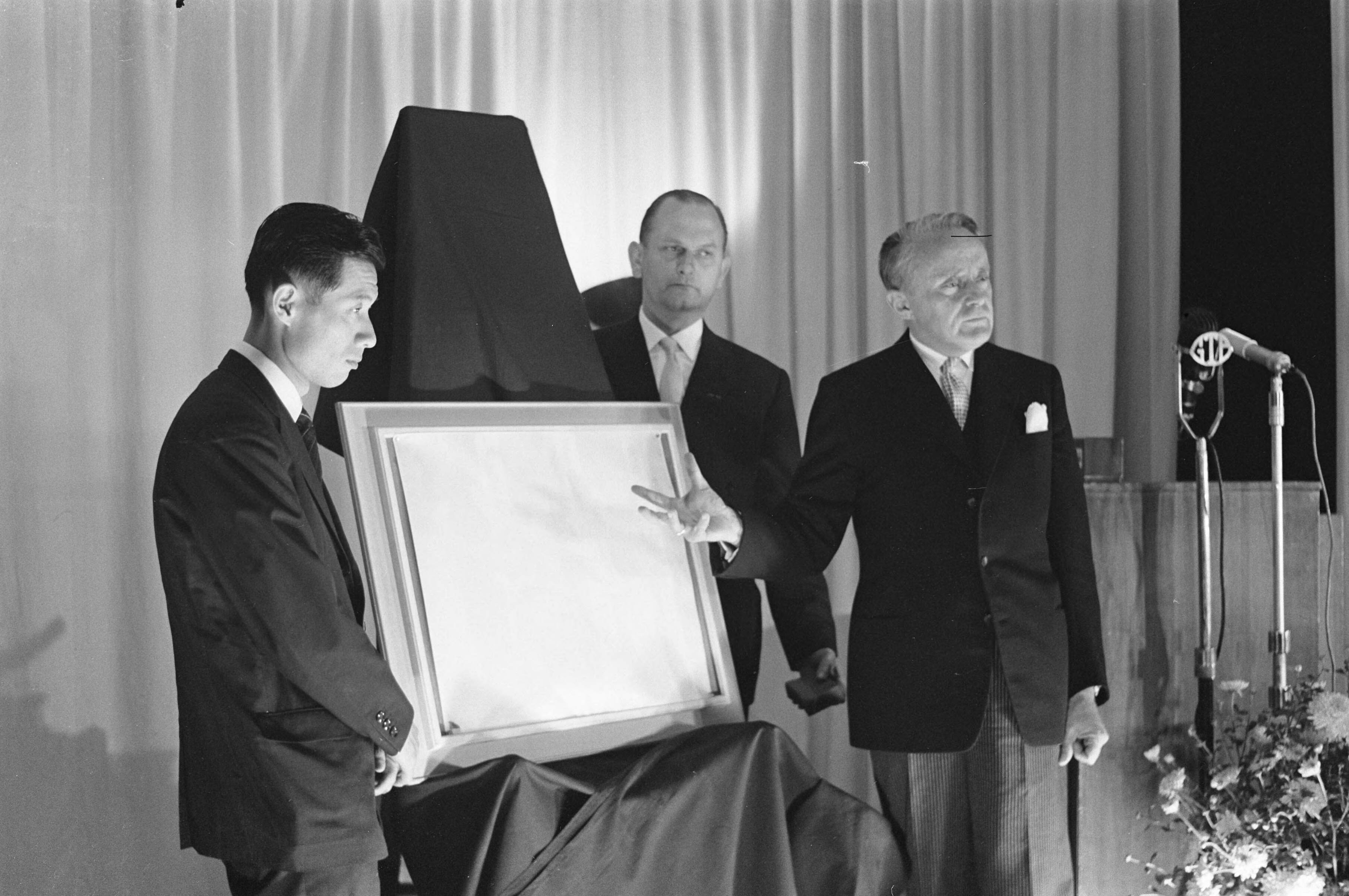 Fotocollectie Anefo — Opening World Press Photo 1961. Commissaris der Koningin in Zuid-Holland mr. J. Klaasesz en de Japanse fotograaf Yasushi Nagao met de winnende foto. Tussen hen in voorzitter Peter van Breukelen — Foto: Pot, Harry / Anefo. Licentie: Set B: Rechtenvrij / Publiek Domein. Bron: Nationaal Archief. http://hdl.handle.net/10648/a9e4ee66-d0b4-102d-bcf8-003048976d84
