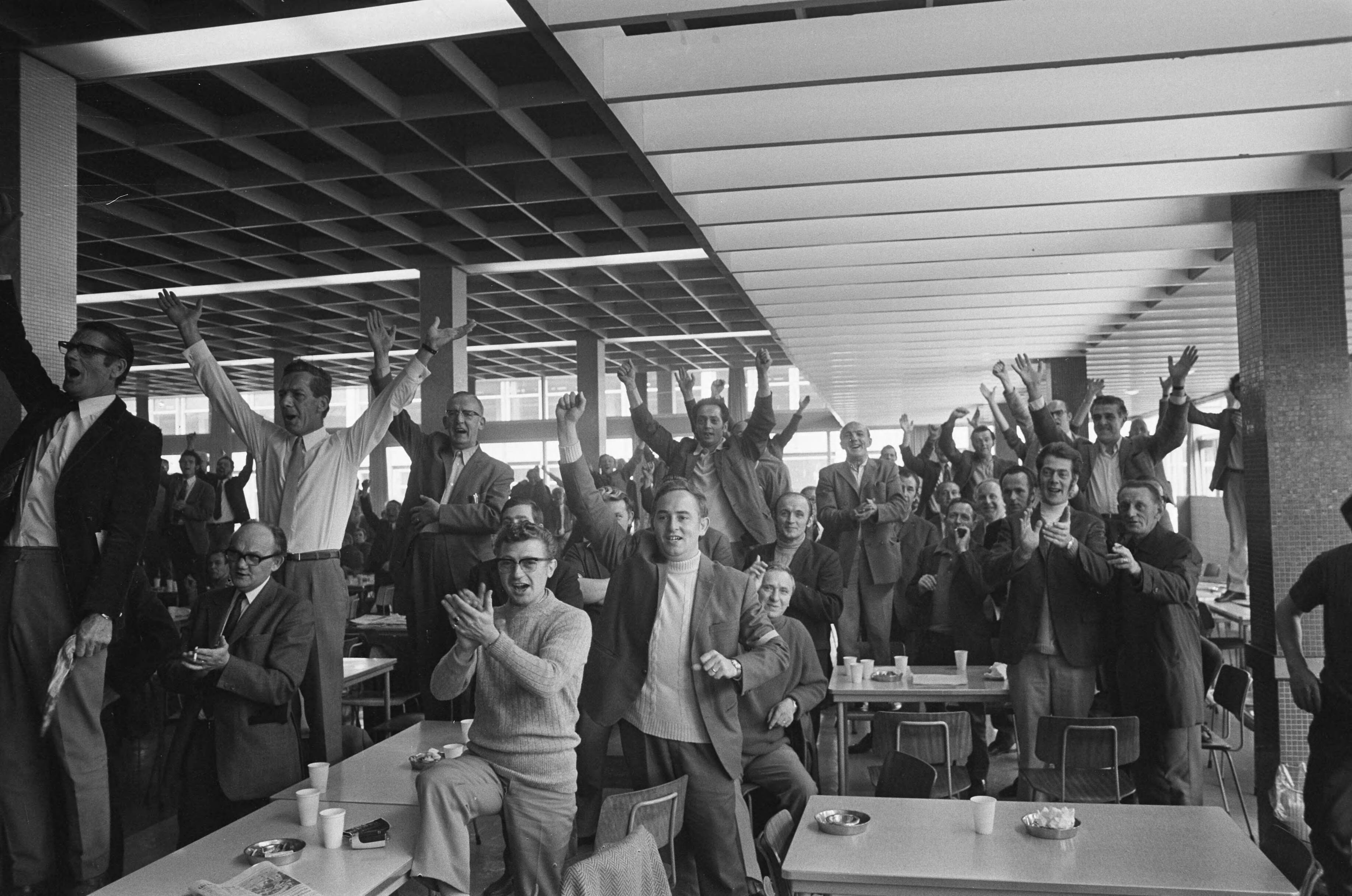 Fotocollectie Anefo — Bezetting ENKA Breda wordt opgeheven, overzicht juichende bezetters in de kantine — Foto: Evers, Joost / Anefo. Licentie: Set B: Rechtenvrij / Publiek Domein. Bron: Nationaal Archief. http://hdl.handle.net/10648/abf6e132-d0b4-102d-bcf8-003048976d84