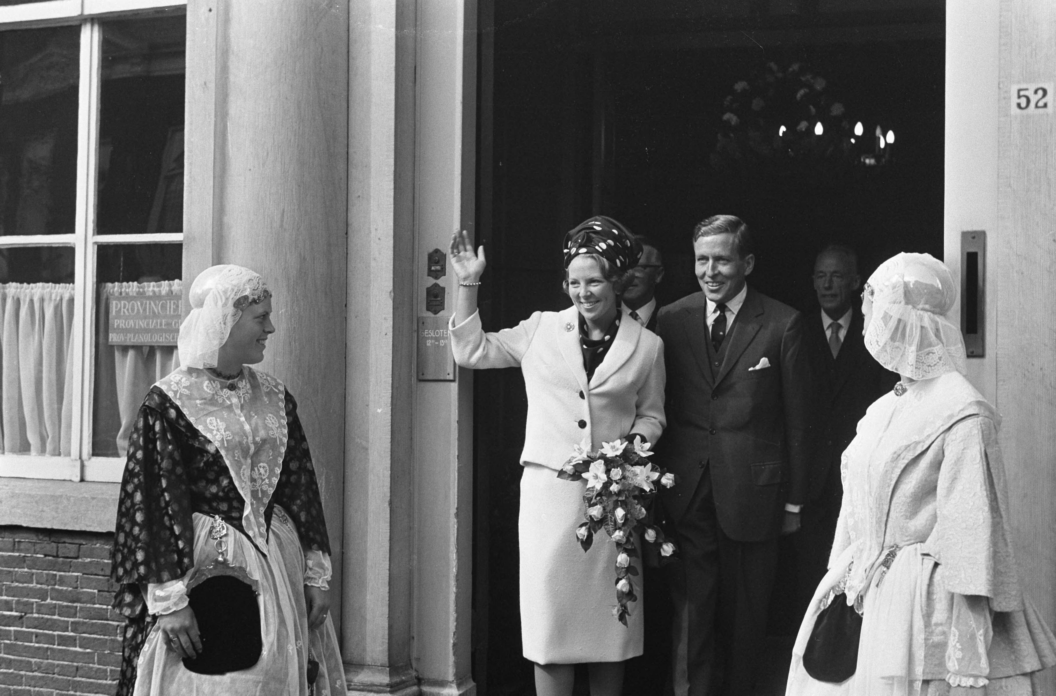 Bezoek van prinses Beatrix en Claus von Amsberg aan de drie noordelijke provincies — Bezoek prinses Beatrix en haar verloofde Claus von Amsberg aan Leeuwarden, het paar bij het Provinciehuis, aan weerszijden twee meisjes in Friese klederdracht — Foto: Evers, Joost / Anefo. Licentie: Set B: Rechtenvrij / Publiek Domein. Bron: Nationaal Archief. http://hdl.handle.net/10648/aabef9bc-d0b4-102d-bcf8-003048976d84