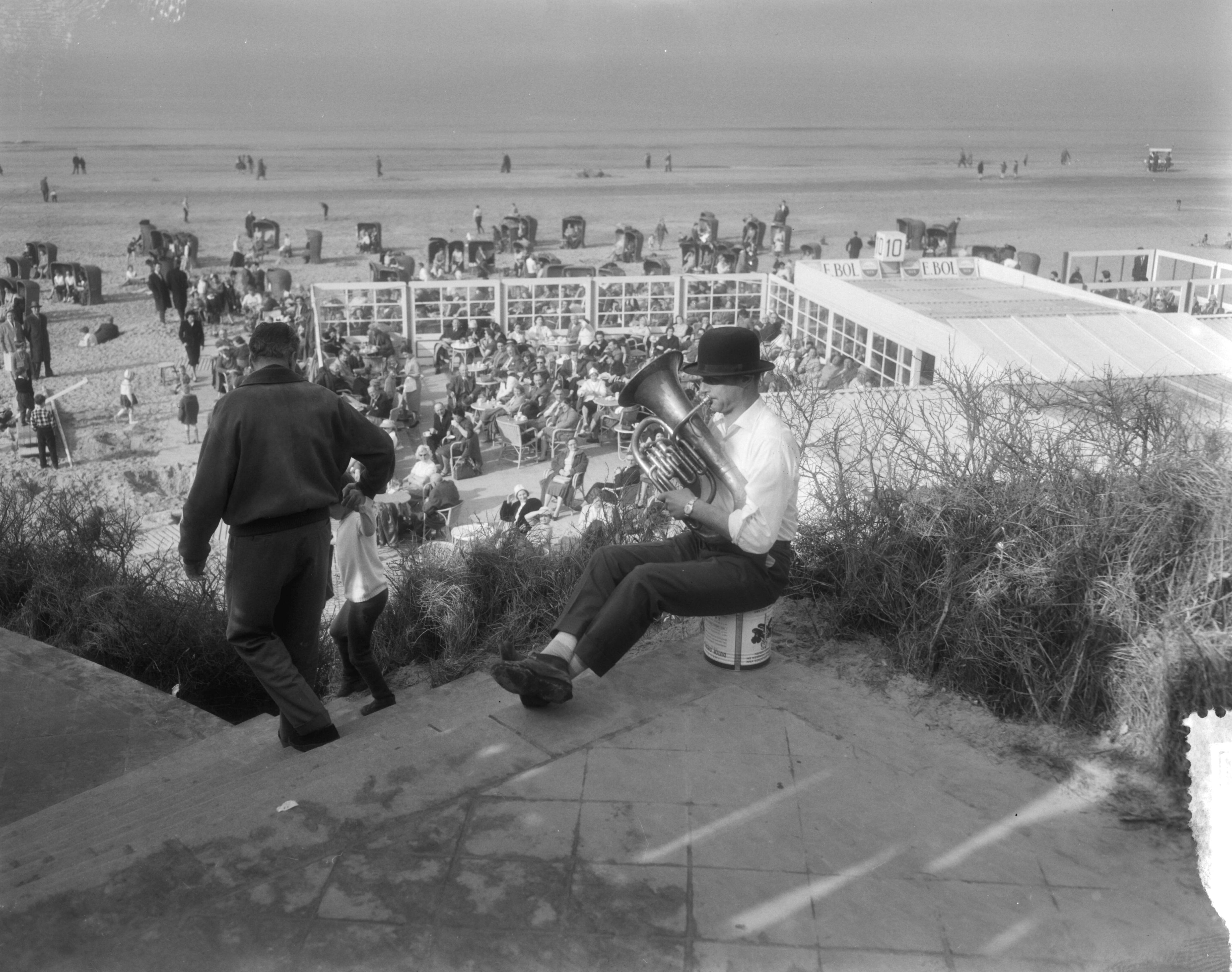 Fotocollectie Anefo — Drukte aan het strand te Zandvoort i.v.m. het mooie weer. Muzikant met tuba en bolhoed — Foto: Pot, Harry / Anefo. Licentie: Set B: Rechtenvrij / Publiek Domein. Bron: Nationaal Archief. http://hdl.handle.net/10648/a98eae16-d0b4-102d-bcf8-003048976d84