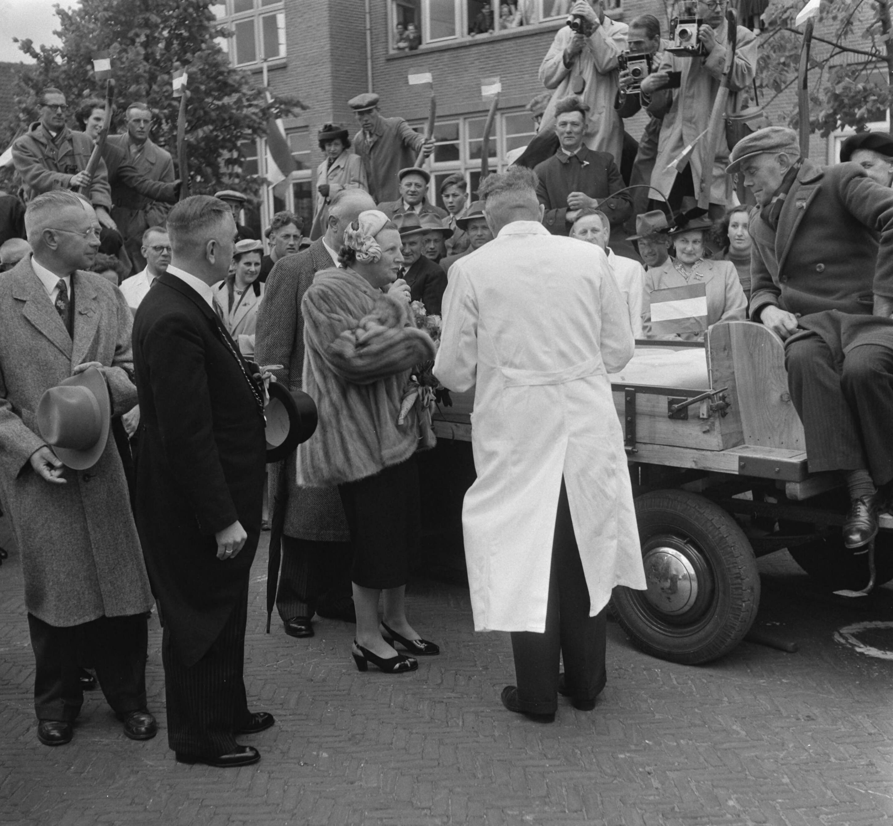 Koninklijk bezoek aan 15 gemeentes in Zuid-Holland (Rijnstreek en Merengebied) — Koningin Juliana en prins Bernhard bezoeken de Kaasmarkt te Woerden. De koningin en een keurmeester proeven van de aangevoerde kaas — Foto: Noske, J.D. / Anefo. Licentie: Set B: Rechtenvrij / Publiek Domein. Bron: Nationaal Archief. http://hdl.handle.net/10648/a92240d2-d0b4-102d-bcf8-003048976d84