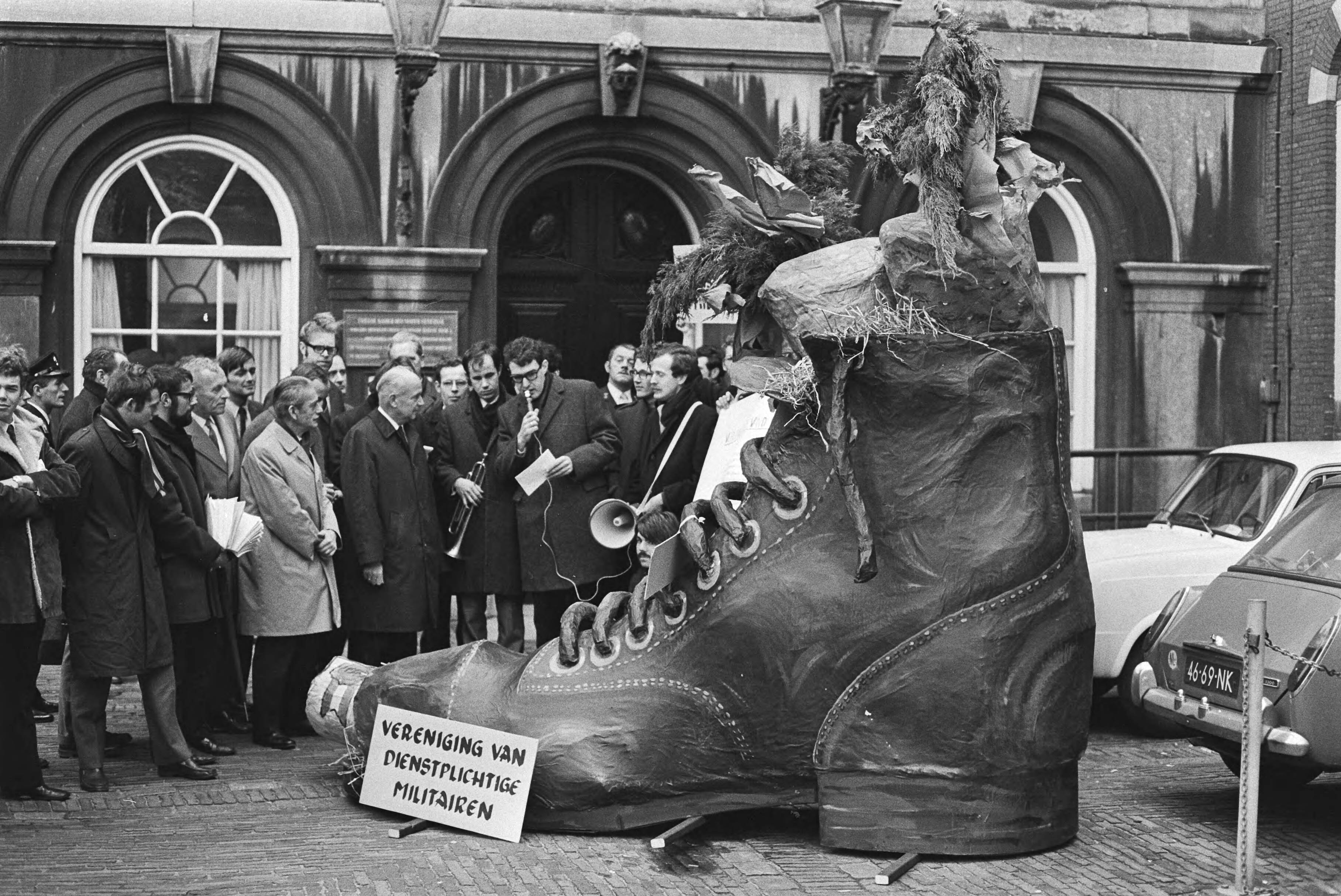 Fotocollectie Anefo — Ver. dienstplichtige militairen schoen met verlanglijst leden Tweede Kamer, Binnenhof, Den Haag; Nederhorst neemt schoen in ontvangst — Foto: Evers, Joost / Anefo. Licentie: Set B: Rechtenvrij / Publiek Domein. Bron: Nationaal Archief. http://hdl.handle.net/10648/abac1364-d0b4-102d-bcf8-003048976d84