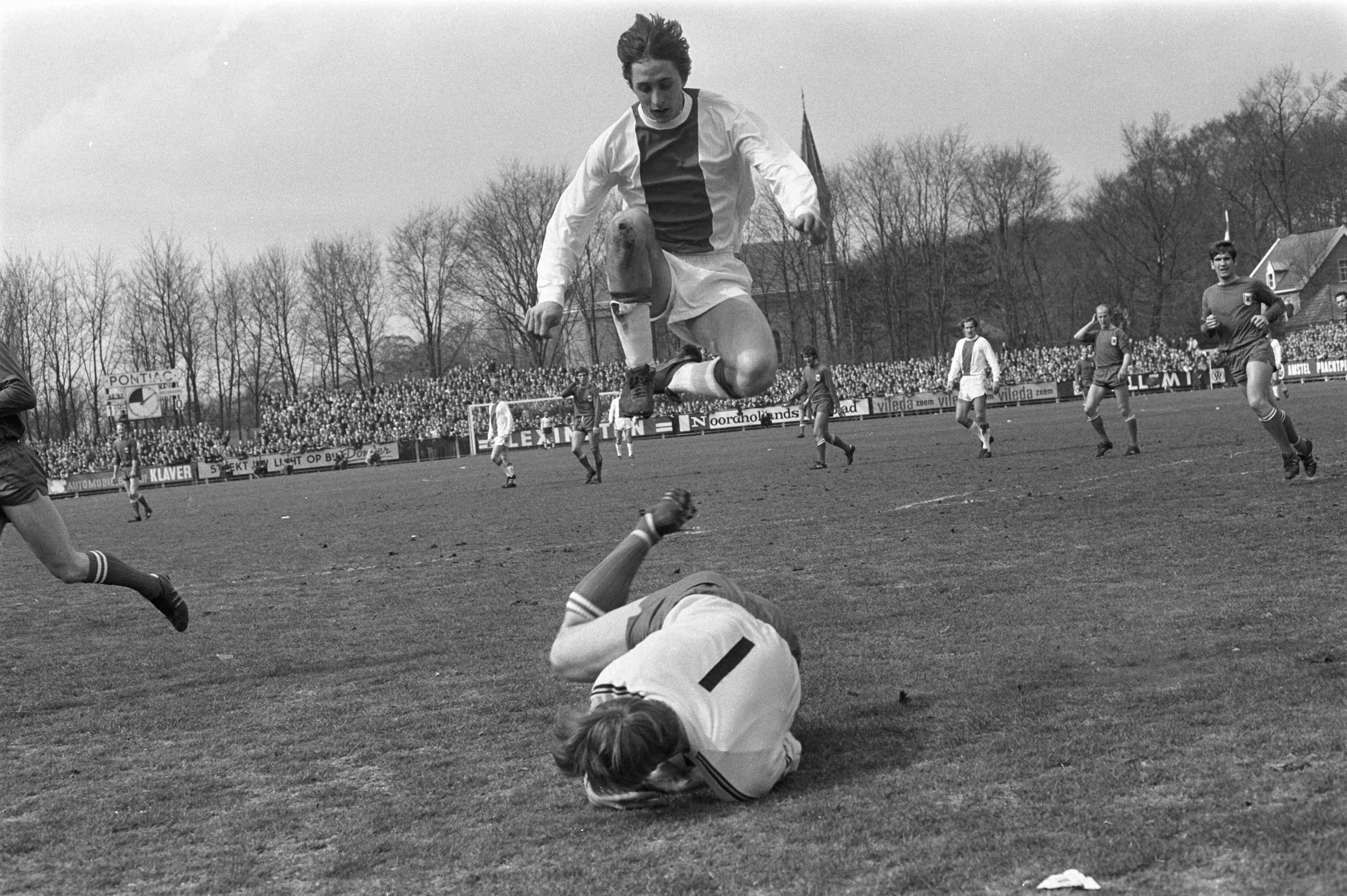 AZ 67 tegen Ajax: 2-1 — Johan Cruijff springt hoog over keeper Gerrit Vooys — Foto: Fotograaf Onbekend / Anefo. Licentie: Set B: Rechtenvrij / Publiek Domein. Bron: Nationaal Archief. http://hdl.handle.net/10648/ab93bcce-d0b4-102d-bcf8-003048976d84
