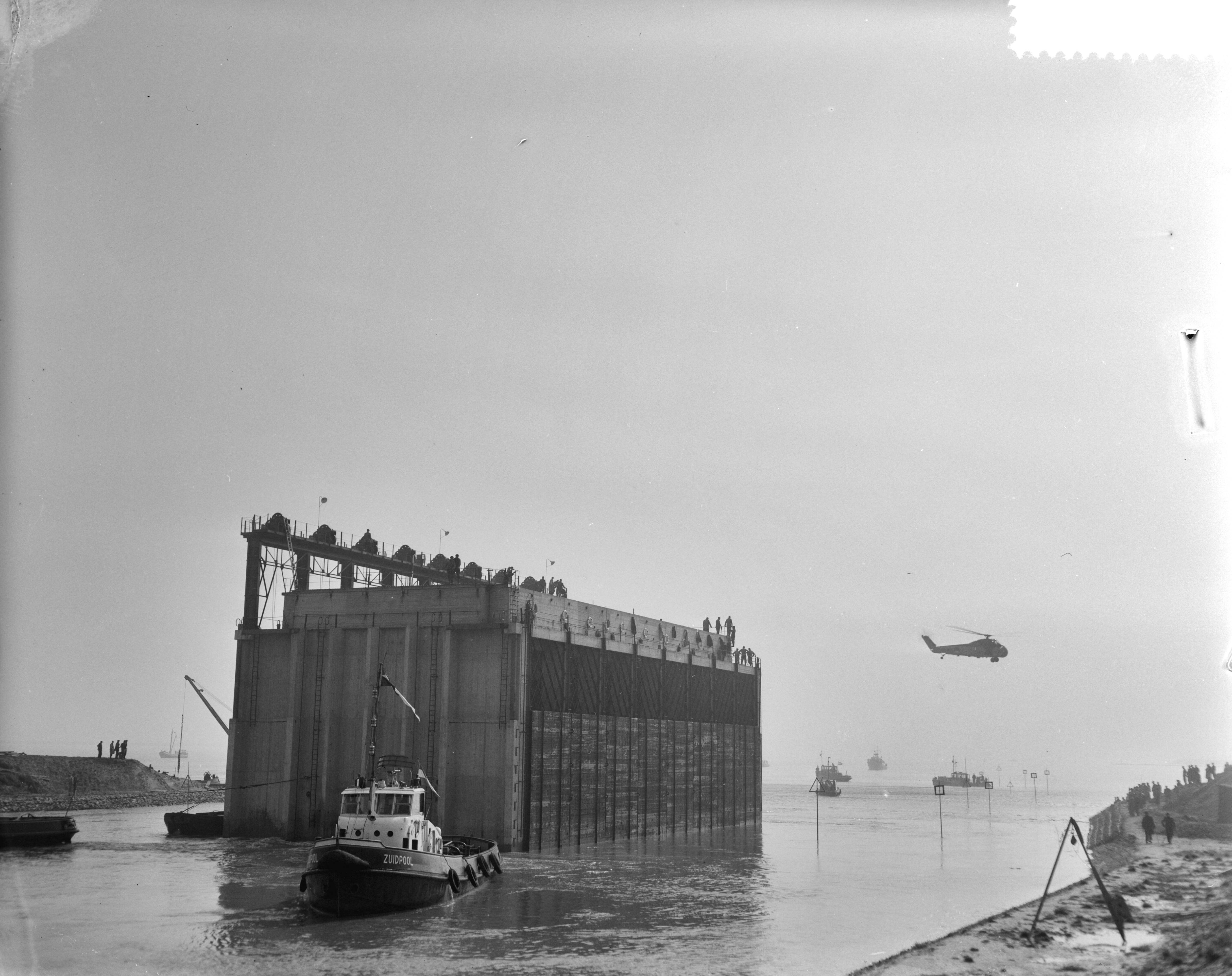 Fotocollectie Anefo — Eerste caisson wordt in het Veerse Gat gevaren — Foto: Faber, […] / Anefo. Licentie: Set B: Rechtenvrij / Publiek Domein. Bron: Nationaal Archief. http://hdl.handle.net/10648/a9d0db56-d0b4-102d-bcf8-003048976d84