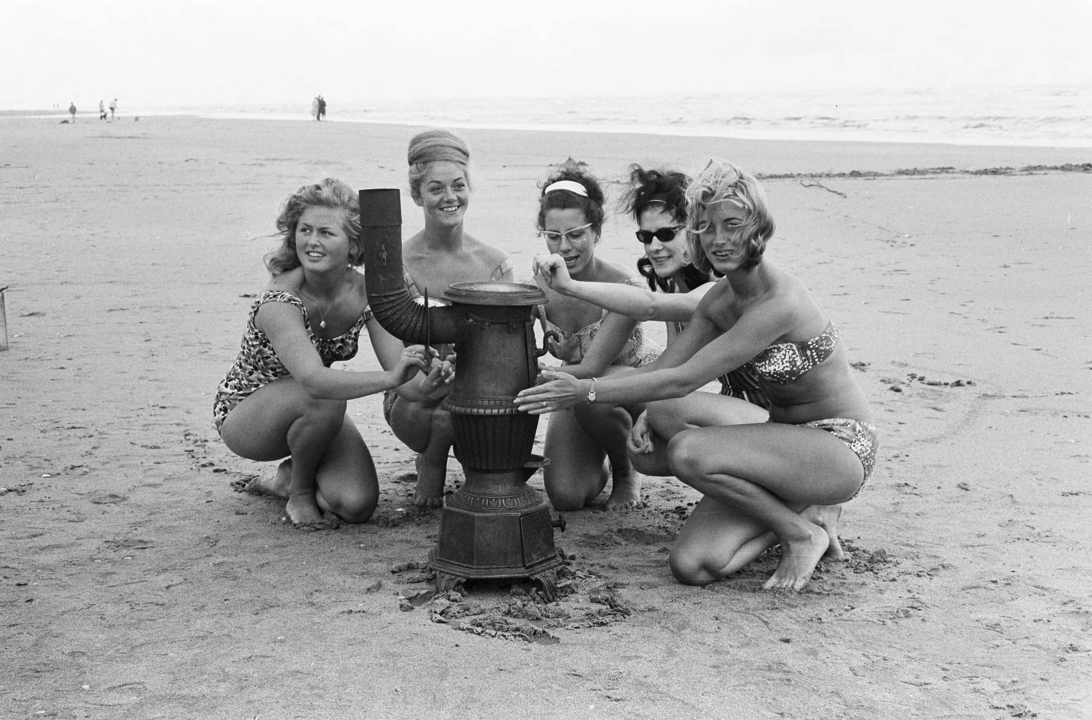 Fotocollectie Anefo — Slecht weer strand Zandvoort. Vijf vrouwelijke optimisten rond een kachel op het strand — Foto: Pot, Harry / Anefo. Licentie: Set B: Rechtenvrij / Publiek Domein. Bron: Nationaal Archief. http://hdl.handle.net/10648/aa0f5c46-d0b4-102d-bcf8-003048976d84