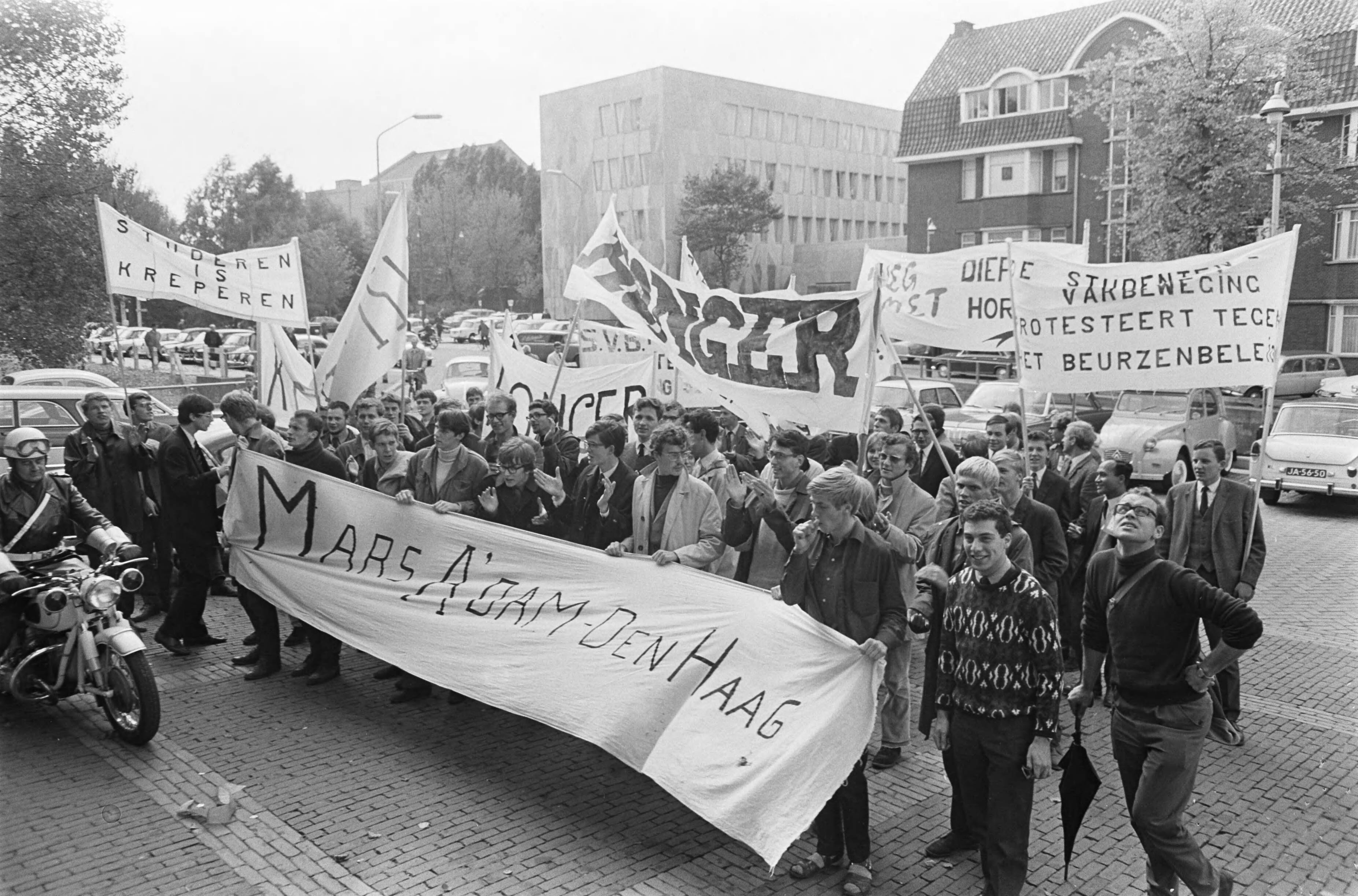 Studentendemonstratie inzake studietoelage, optocht van Amsterdam naar Den Haag — Betogende studenten ariveren bij het ministerie van OKW — Foto: Fotograaf Onbekend / Anefo. Licentie: Set B: Rechtenvrij / Publiek Domein. Bron: Nationaal Archief. http://hdl.handle.net/10648/aafe6b6a-d0b4-102d-bcf8-003048976d84