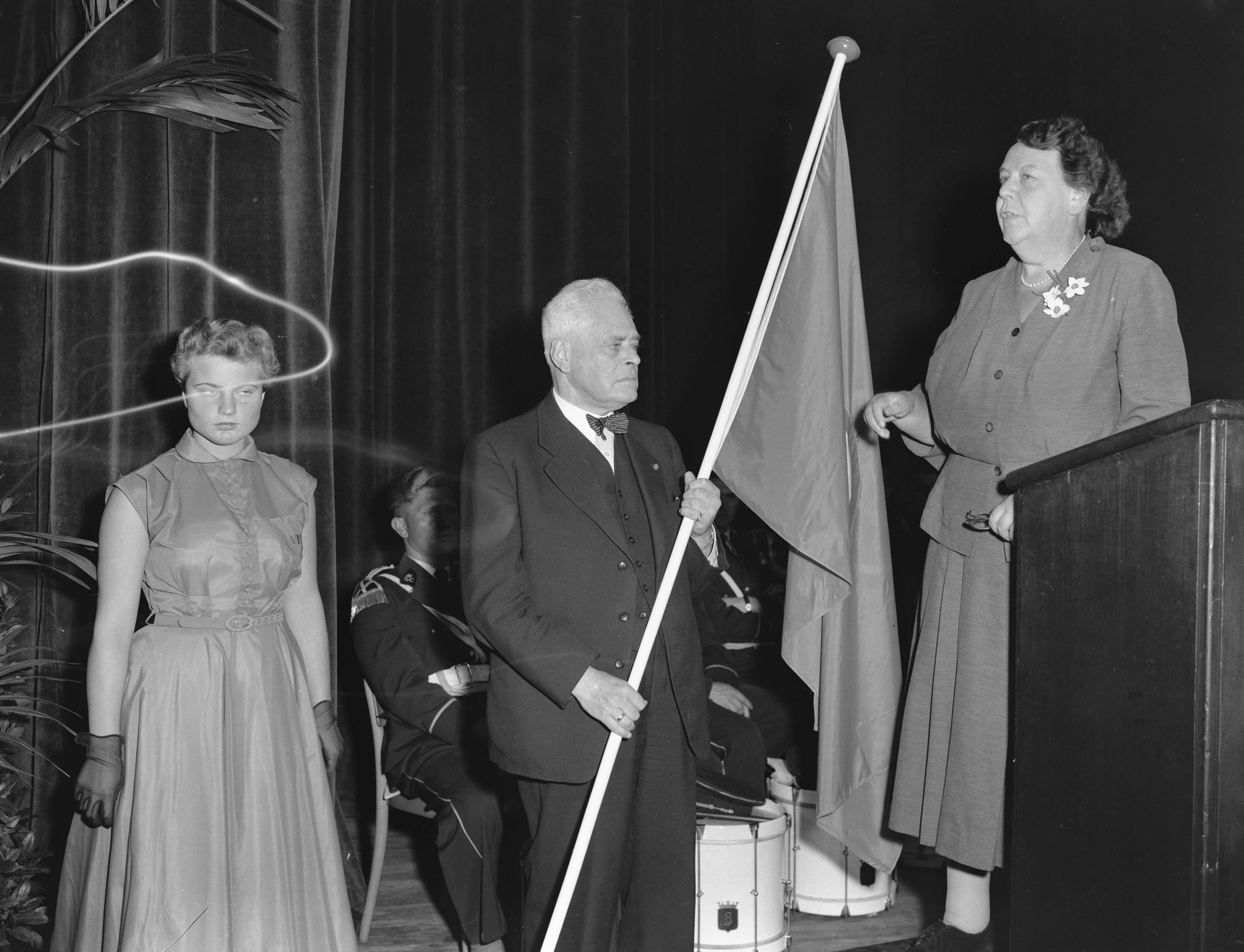 Fotocollectie Anefo — VVD-dag te Scheveningen. Mevr. mr. F.A.J. Scheltema-Conradi heeft de nieuwe [blauwe] partijvlag overhandigd aan partijvoorzitter prof. mr. P.J. Oud. Links een lid van de jongerenorganisatie J.O.V.D. — Foto: Pot, Harry / Anefo. Licentie: Set B: Rechtenvrij / Publiek Domein. Bron: Nationaal Archief. http://hdl.handle.net/10648/a93b1e36-d0b4-102d-bcf8-003048976d84
