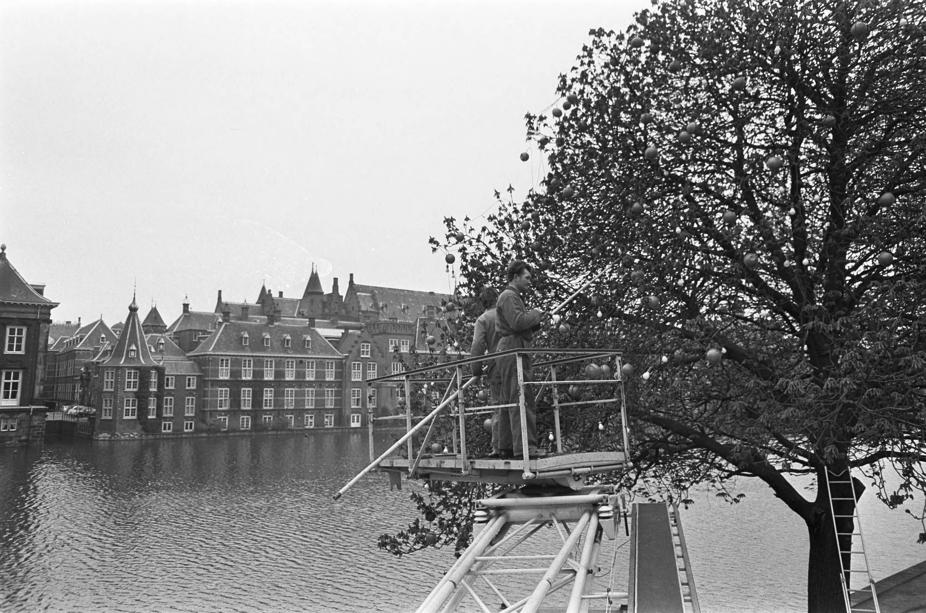 Fotocollectie Anefo — Aanbrengen versiering (oranjeballen) op de Lange Vijverberg te Den Haag — Foto: Nijs, Jac. de / Anefo. Licentie: Set B: Rechtenvrij / Publiek Domein. Bron: Nationaal Archief. http://hdl.handle.net/10648/ab154330-d0b4-102d-bcf8-003048976d84