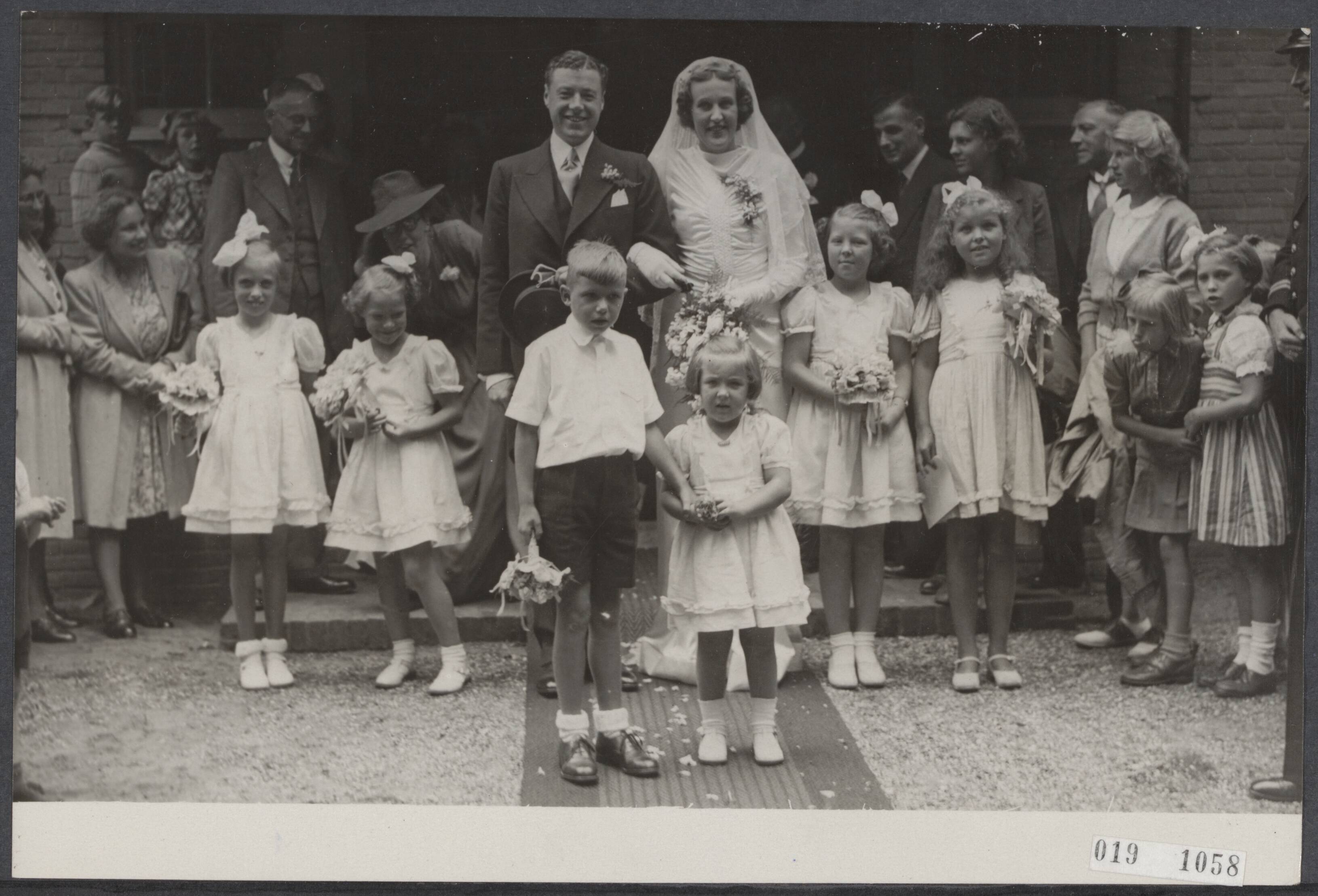 Fotocollectie Elsevier Binnenland — In de Doopsgezinde Kerk te Baarn werd het huwelijk ingezegend tussen W.G. Cavius en zuster A. Huidekoper, verzorgster van de prinsessen. Het bruidspaar bij het verlaten van de kerk. LInks van het bruidspaar prinses Irene, rechts prinses Beatrix en voor het bruidspaar prinses Margriet — Foto: ANP / RVD of rechtenvrij. Licentie: Set B: Rechtenvrij / Publiek Domein. Bron: Nationaal Archief. http://hdl.handle.net/10648/adc87cc8-d0b4-102d-bcf8-003048976d84