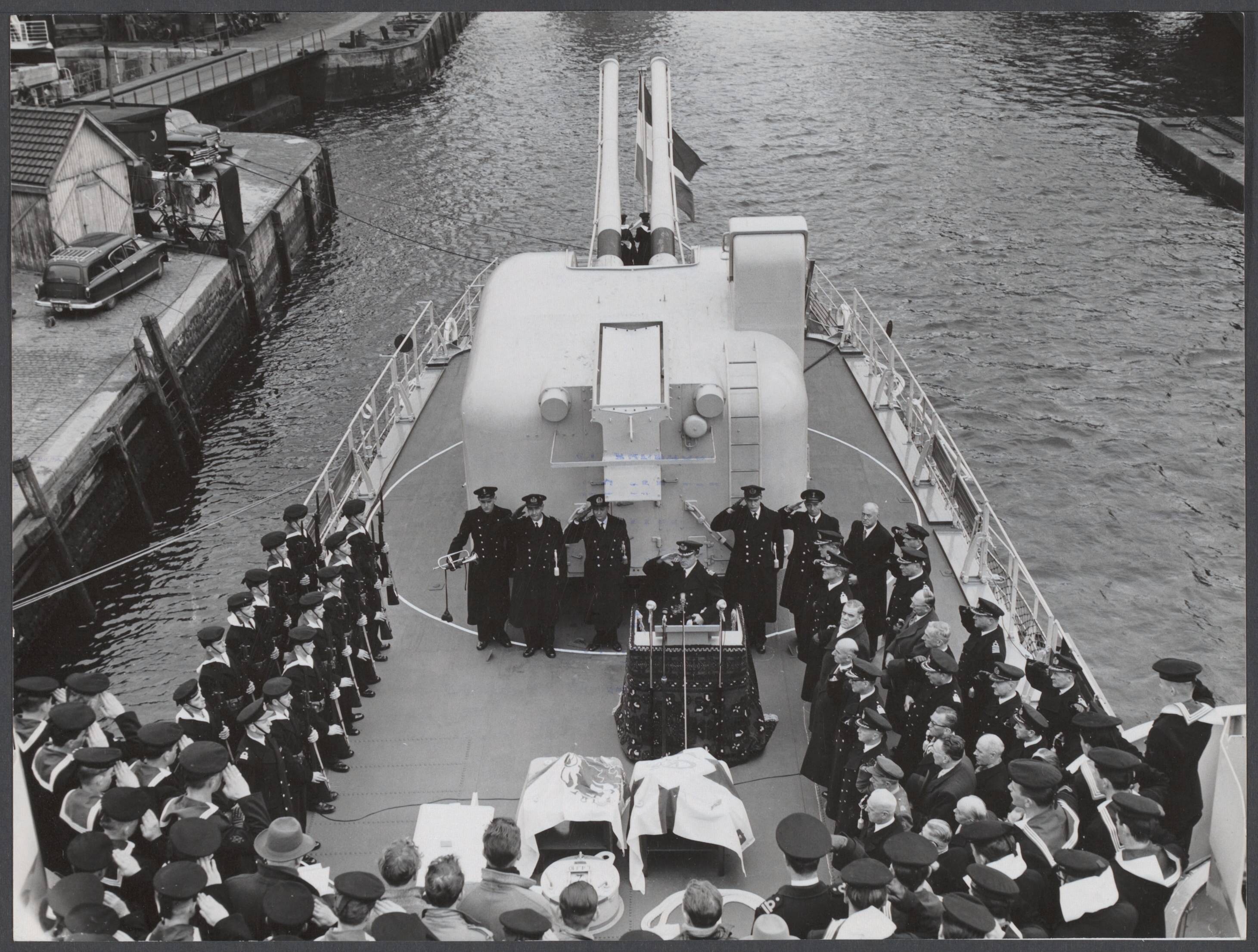 Onderzeebootjagers, alph. op naam H t/m Z - Nederland — Woensdag is Hr. Ms. onderzeebootjager 'Limburg' op de werf van "De Schelde" te Vlissingen in dienst gesteld. De "Limburg" is een B-klasse onderzeebootjager, die door prinses Beatrix op 5 september 1955 te water werd gelaten. De "Limburg" tijdens de indienststelling. De vlag wordt op commando van de commandant, kapitein-luitenant ter zee jhr. P.L.M. van Geen , gehesen. De commandant staat achter de katheder — Foto: Rossem, Wim van / Anefo. Licentie: Set B: Rechtenvrij / Publiek Domein. Bron: Nationaal Archief. http://hdl.handle.net/10648/916a0fcd-f083-6ff8-c856-4d1c1e28f65a