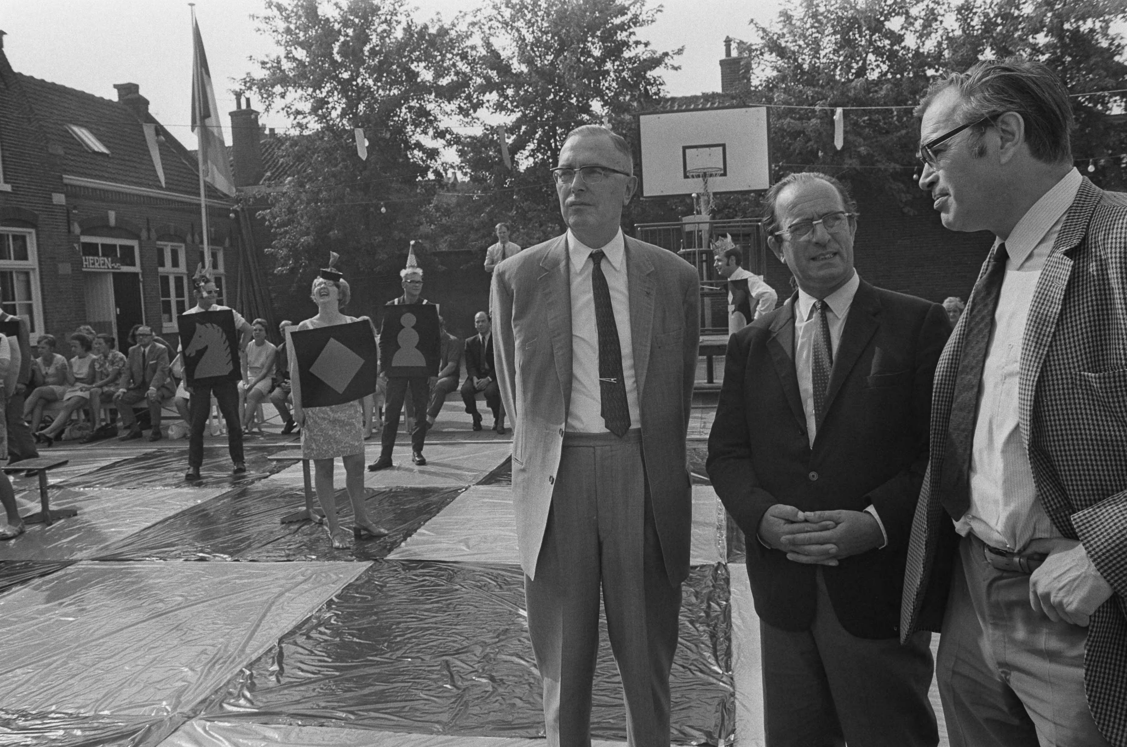 Fotocollectie Anefo — Godfried Bomans en dr. Max Euwe spelen schaakspel met levende stukken, Haarlem — Foto: Mieremet, Rob / Anefo. Licentie: Set B: Rechtenvrij / Publiek Domein. Bron: Nationaal Archief. http://hdl.handle.net/10648/aba130f2-d0b4-102d-bcf8-003048976d84