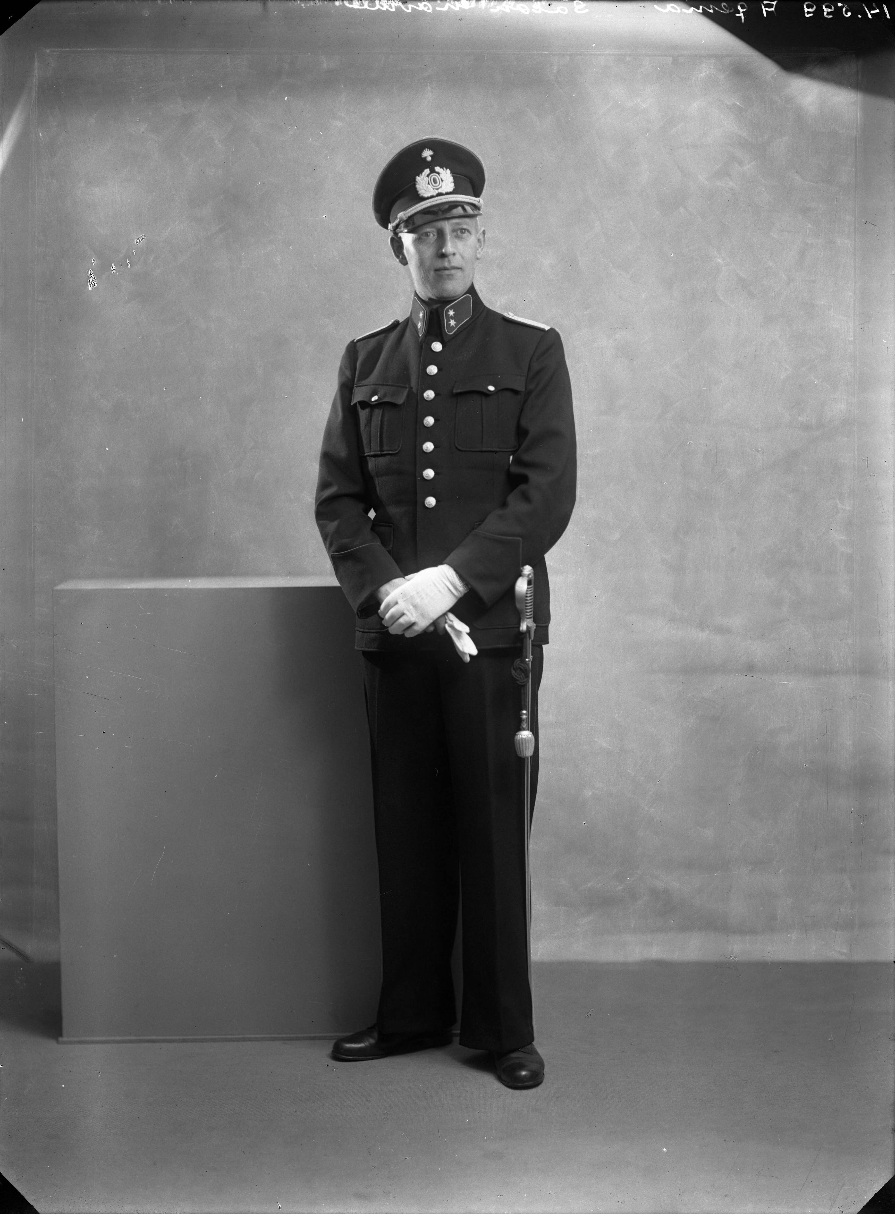 Portretten — Studio-opnames. Portret van een man in politie-uniform met hoge boord, een sabel aan de riem, witte handschoenen en een wijduitstaande uniformpet met klep, koord en lauwerkransembleem. Haarlem, Nederland. 1918-1930. 14.599 Agema salon gravure — Foto: Berg, Th.C.J. van den / Spaarnestad Photo (05887). Licentie: Set B: Rechtenvrij / Publiek Domein. Bron: Nationaal Archief. http://hdl.handle.net/10648/35429da7-c770-a382-e063-6df0900a6686