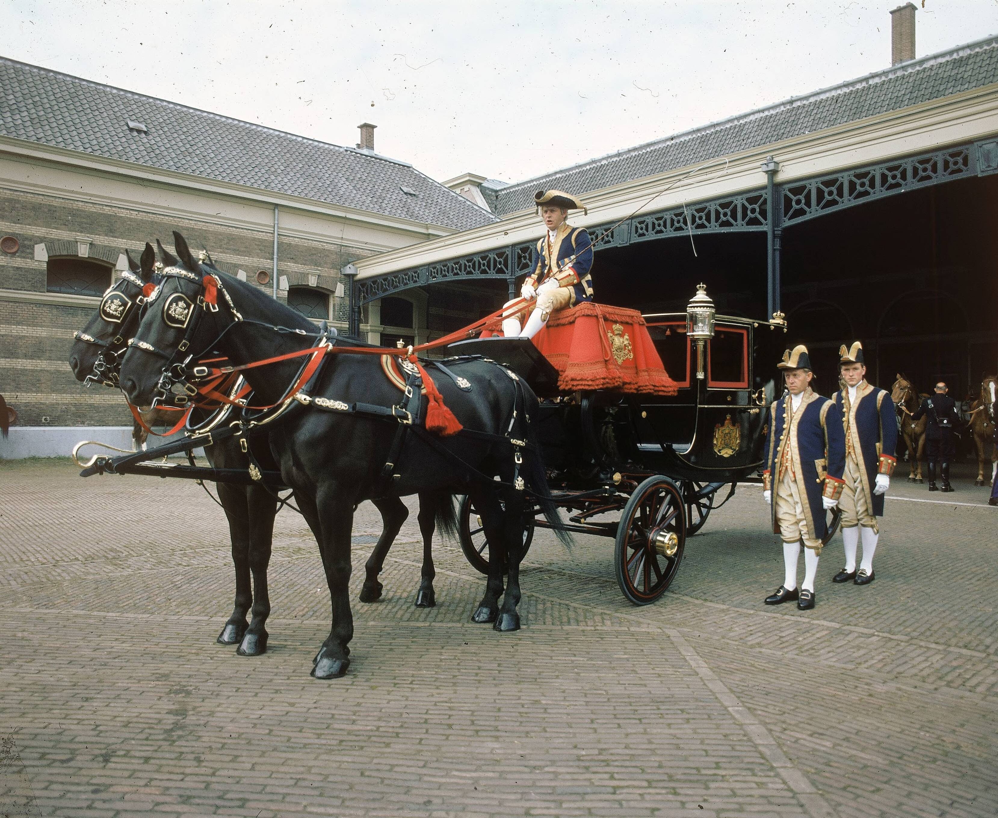 Fotocollectie RVD / Koninklijk Huis — Prinsjesdag - volgrijtuig met koetsier, lakeien en paarden op de binnenplaats van de koninklijke stallen aan de Noordwal in Den Haag — Foto: Mastenbroek, Cees / RVD. Licentie: Set B: Rechtenvrij / Publiek Domein. Bron: Nationaal Archief. http://hdl.handle.net/10648/afb2735e-d0b4-102d-bcf8-003048976d84