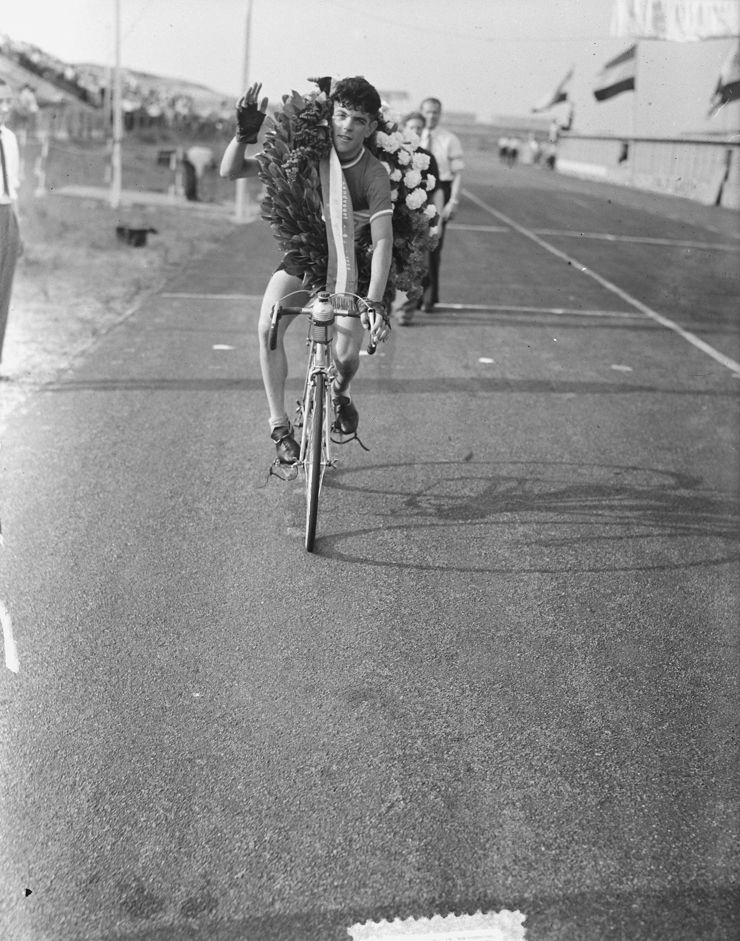 Nederlandse kampioenschap wegwedstrijd wielrennen voor amateurs (1952) — Nederlands kampioenschap wielrennen op de weg voor amateurs op het circuit van Zandvoort. Winnaar Cees Aanraad uit Oud-Gastel tijdens zijn ereronde — Foto: Noske, J.D. / Anefo. Licentie: Set B: Rechtenvrij / Publiek Domein. Bron: Nationaal Archief. http://hdl.handle.net/10648/a8fc98b4-d0b4-102d-bcf8-003048976d84