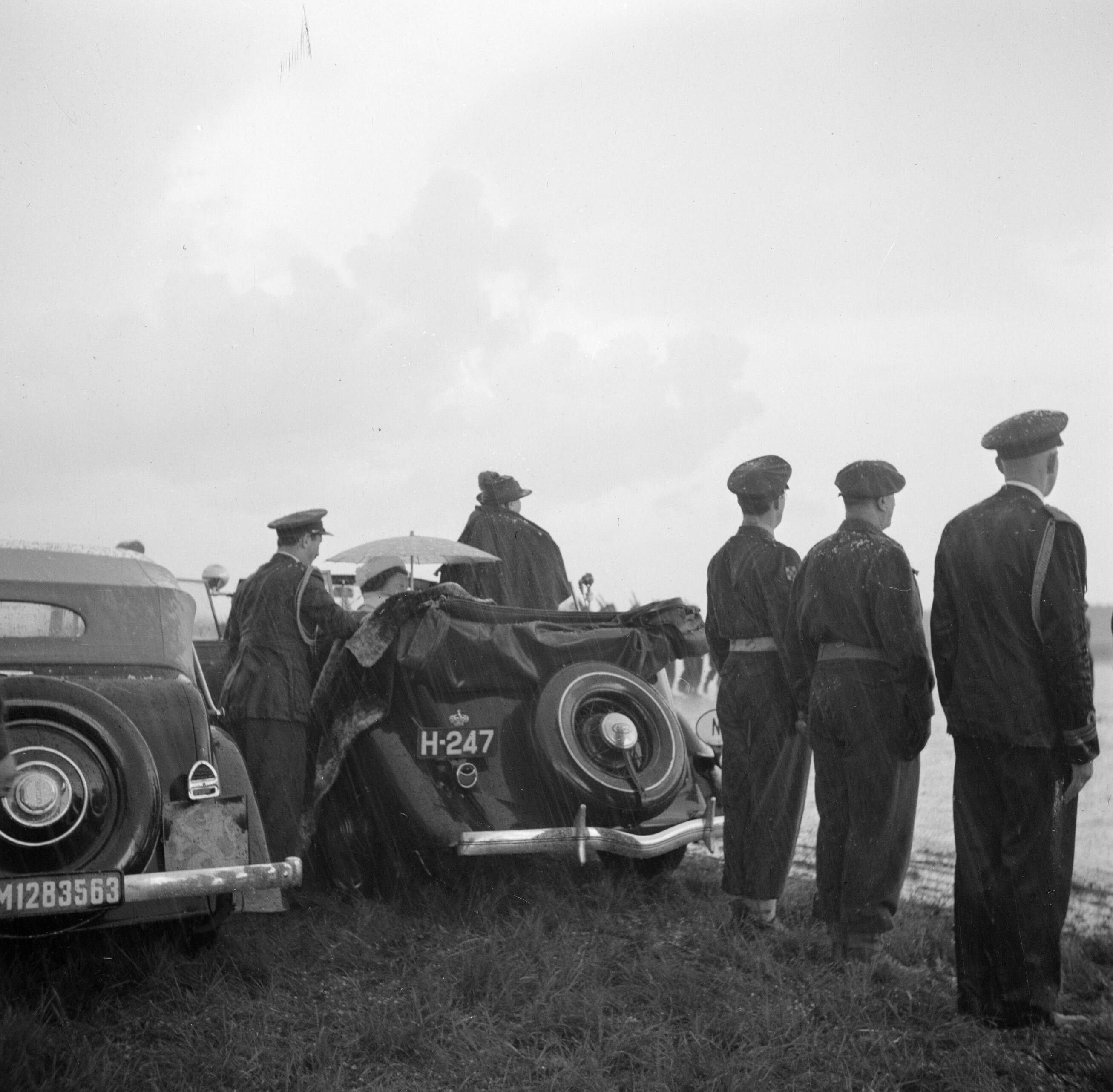Uitreiking van de Militaire Willems-Orde en andere onderscheidingen door koningin Wilhelmina in aanwezigheid van de overige leden van de koninklijke familie op de vliegbasis Soesterberg — Koningin Wilhelmina neemt, staande in een open auto, het defilé van militairen af; naast haar zittend prinses Juliana — Foto: Poll, Willem van de. Licentie: Set B: Rechtenvrij / Publiek Domein. Bron: Nationaal Archief. http://hdl.handle.net/10648/aee8e6d8-d0b4-102d-bcf8-003048976d84