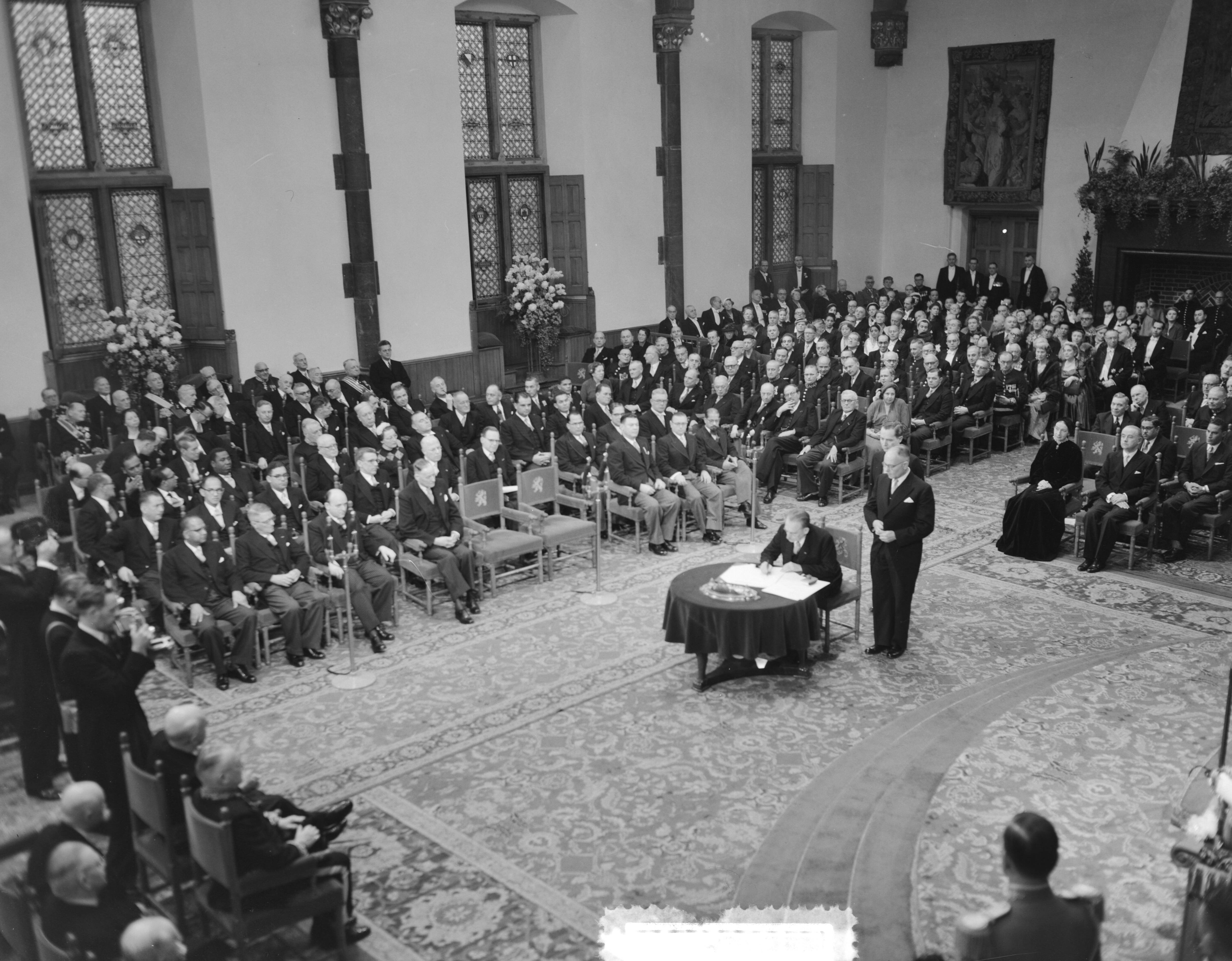 Koningin Juliana ondertekent in een plechtige bijeenkomst in de Ridderzaal in Den Haag de Acte van Bevestiging van het Statuut voor het Koninkrijk — Ondertekening van de Acte van Bevestiging van het Statuut van het Koninkrijk in de Ridderzaal te Den Haag. Verschillende ministers ondertekenen de akte — Foto: Noske, J.D. / Anefo. Licentie: Set B: Rechtenvrij / Publiek Domein. Bron: Nationaal Archief. http://hdl.handle.net/10648/a92e1ec0-d0b4-102d-bcf8-003048976d84