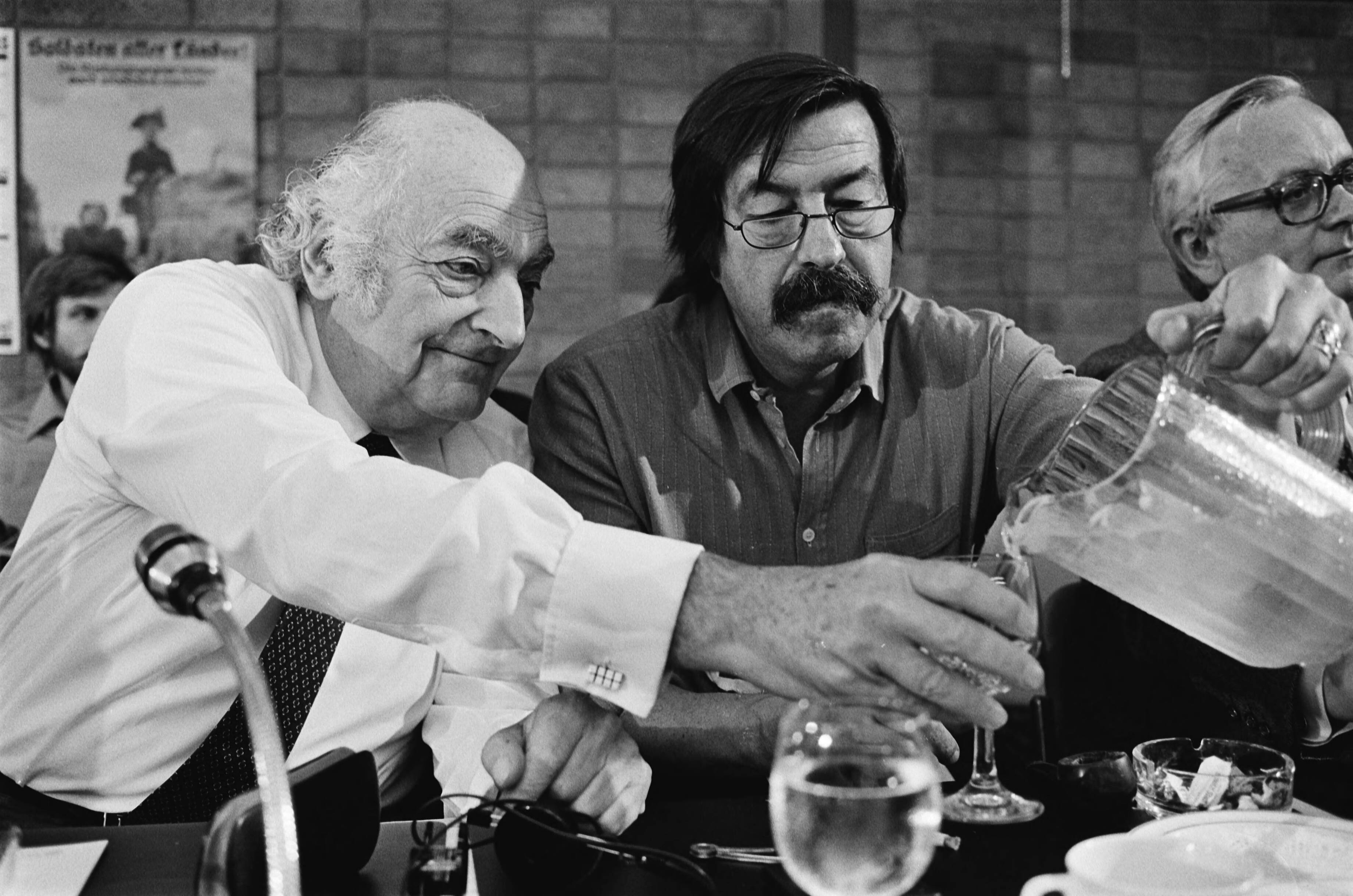 Fotocollectie Anefo — Europese conferentie van schrijvers "Haagse Treffen" in Kurhaus te Scheveningen; Stefan Heym (DDR) (l) en Gunter Grass (BRD) schenkt water in — Foto: Antonisse, Marcel / Anefo. Licentie: Set B: Rechtenvrij / Publiek Domein. Bron: Nationaal Archief. http://hdl.handle.net/10648/ad1857bc-d0b4-102d-bcf8-003048976d84