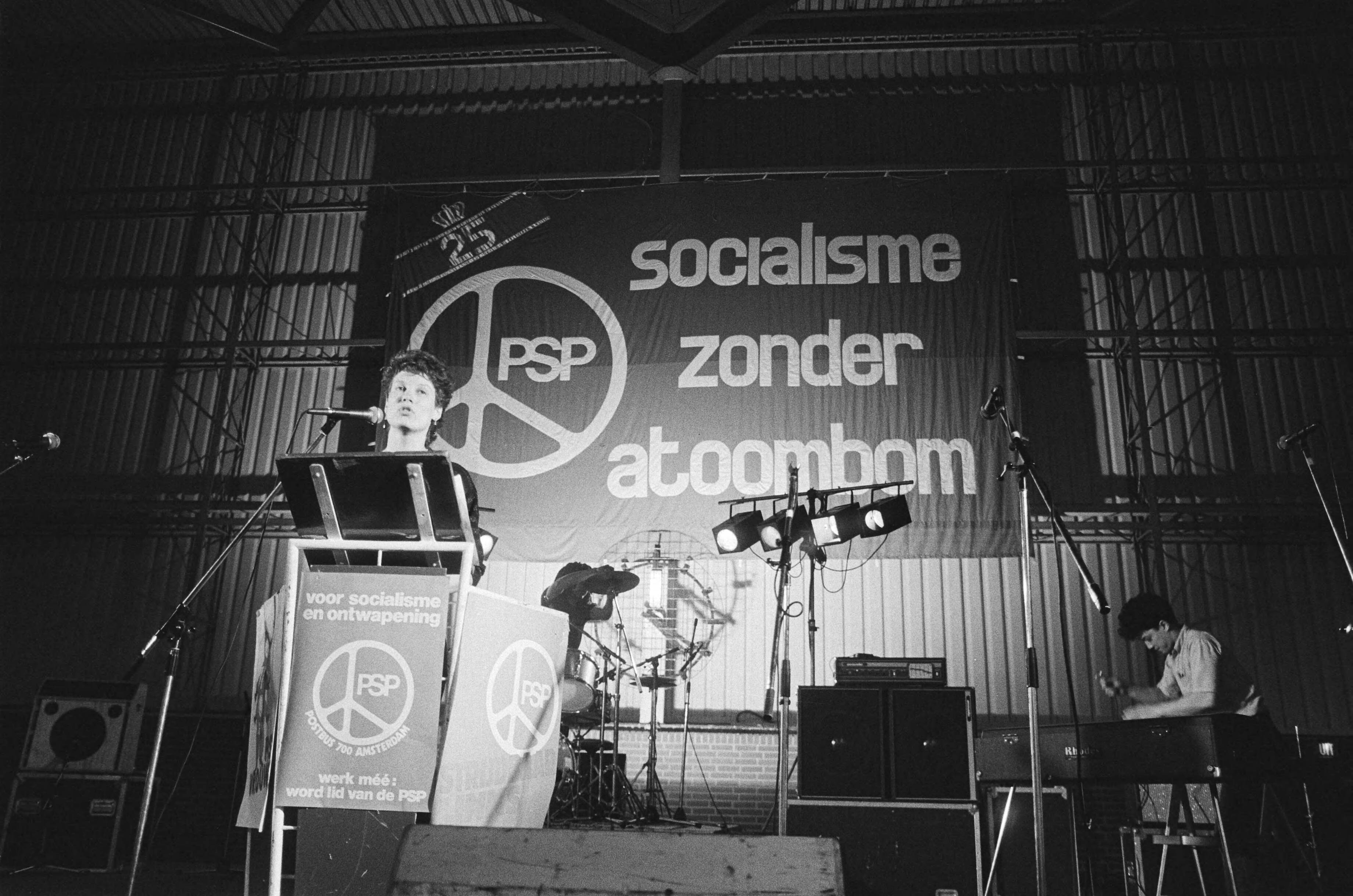 Fotocollectie Anefo — Manifestatie "25 jaar PSP" in Expohal in Hilversum; Andrée van Es aan het woord, met groot spandoek van PSP op achtergrond — Foto: Bogaerts, Rob / Anefo. Licentie: Set B: Rechtenvrij / Publiek Domein. Bron: Nationaal Archief. http://hdl.handle.net/10648/ad181a90-d0b4-102d-bcf8-003048976d84