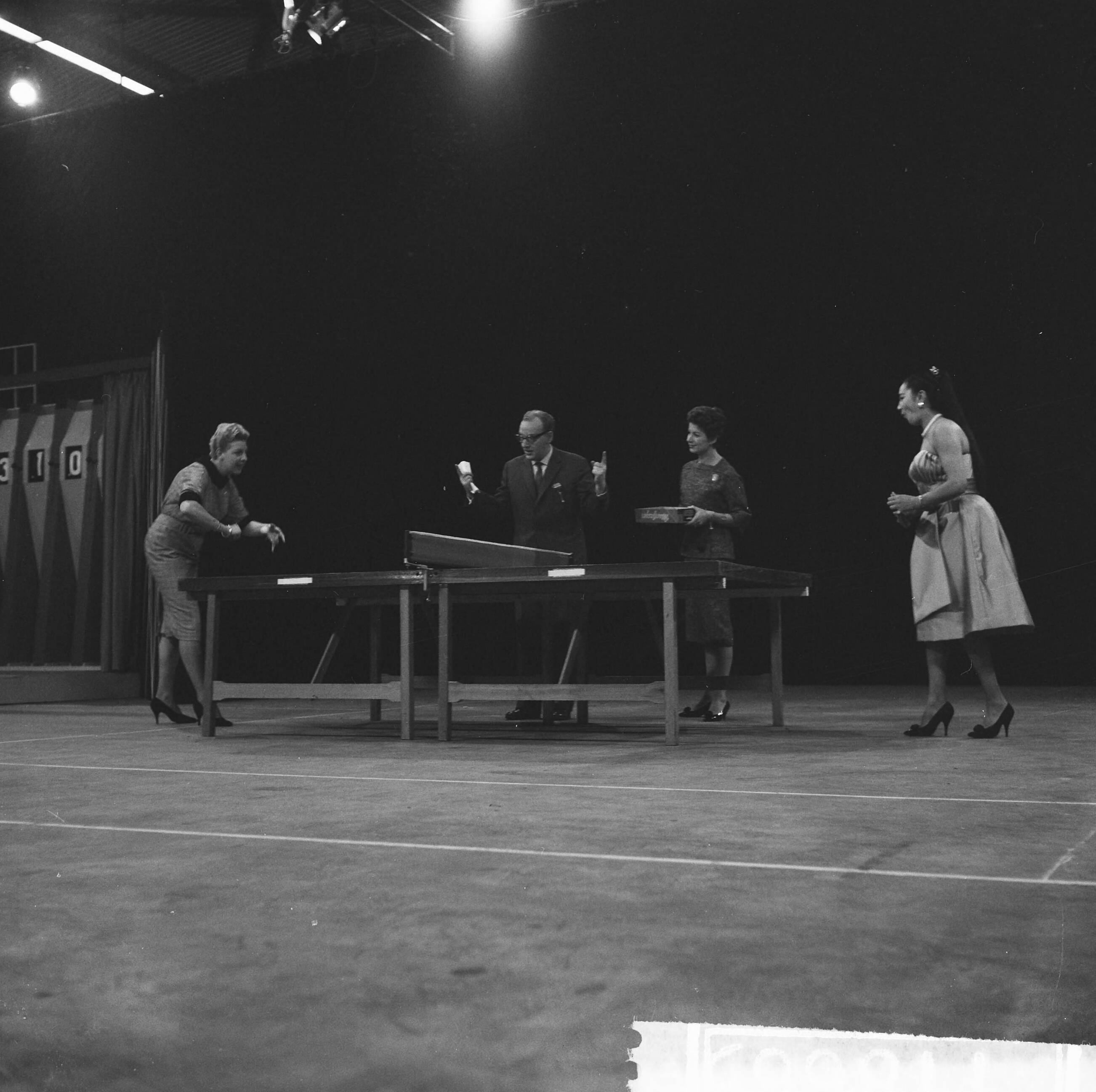Fotocollectie Anefo — Televisieprogramma "TV-Toto" van de VARA uitgezonden vanuit de Expohal, Pia Beck (links) speelt tafeltennis met Sanny Day, de vroegere zangeres van de Milllers. In het midden presentator Theo Eerdmans en zijn assistente Maud — Foto: Lindeboom, Henk / Anefo. Licentie: Set B: Rechtenvrij / Publiek Domein. Bron: Nationaal Archief. http://hdl.handle.net/10648/a9c249c4-d0b4-102d-bcf8-003048976d84